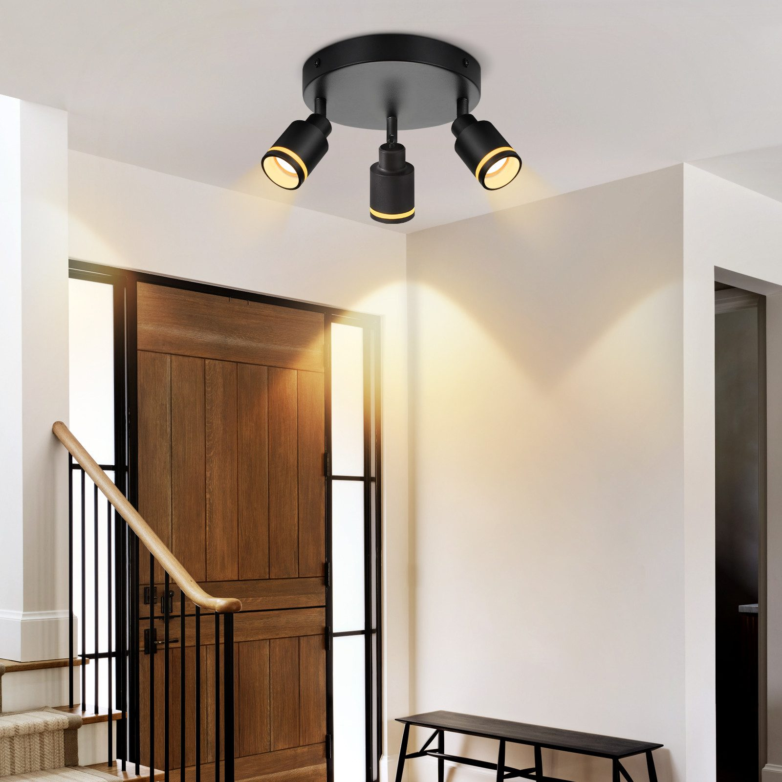 Lampada da soffitto con tre faretti orientabili, finitura nera, illumina un corridoio.