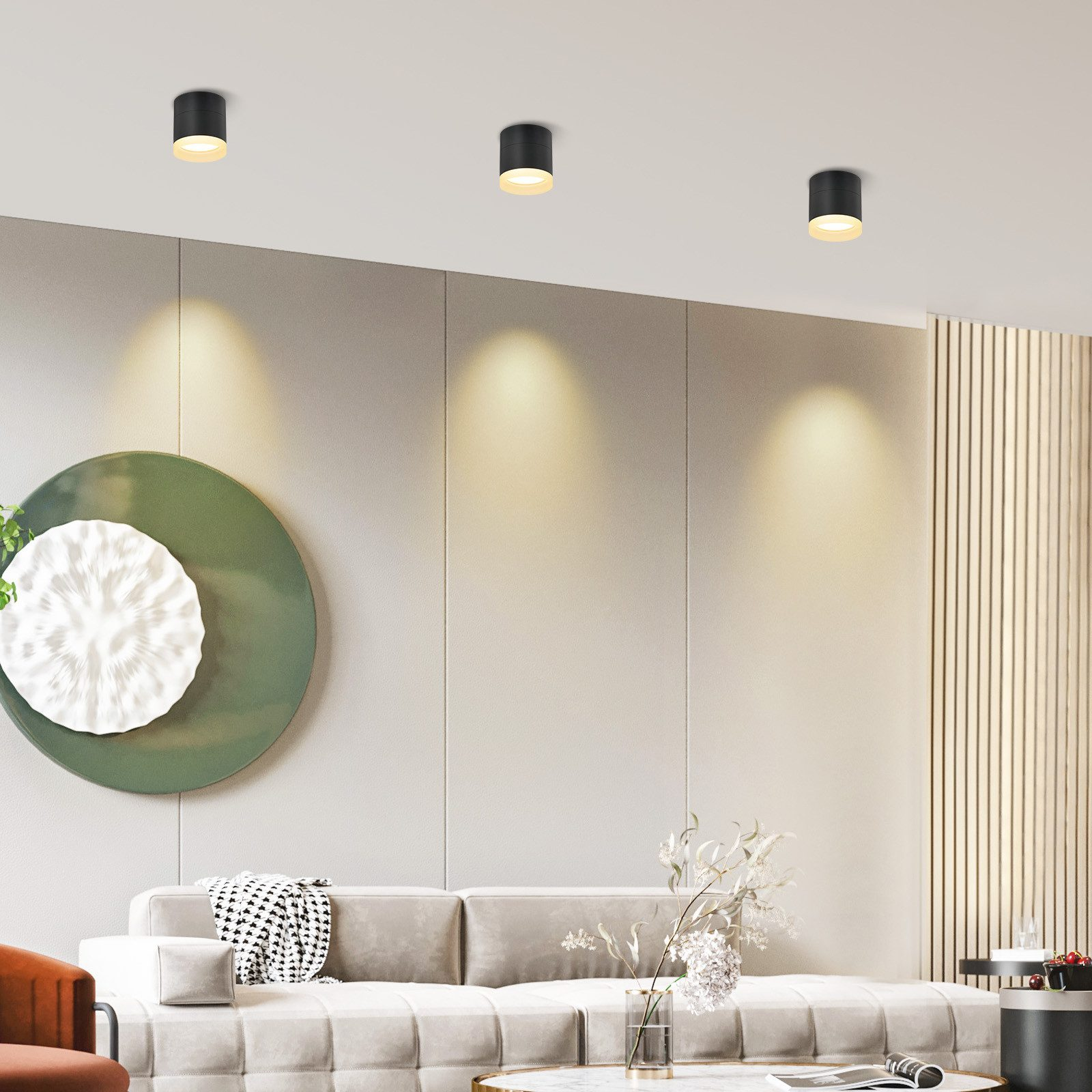Un moderno soggiorno con faretti a soffitto, un divano ed elementi decorativi.