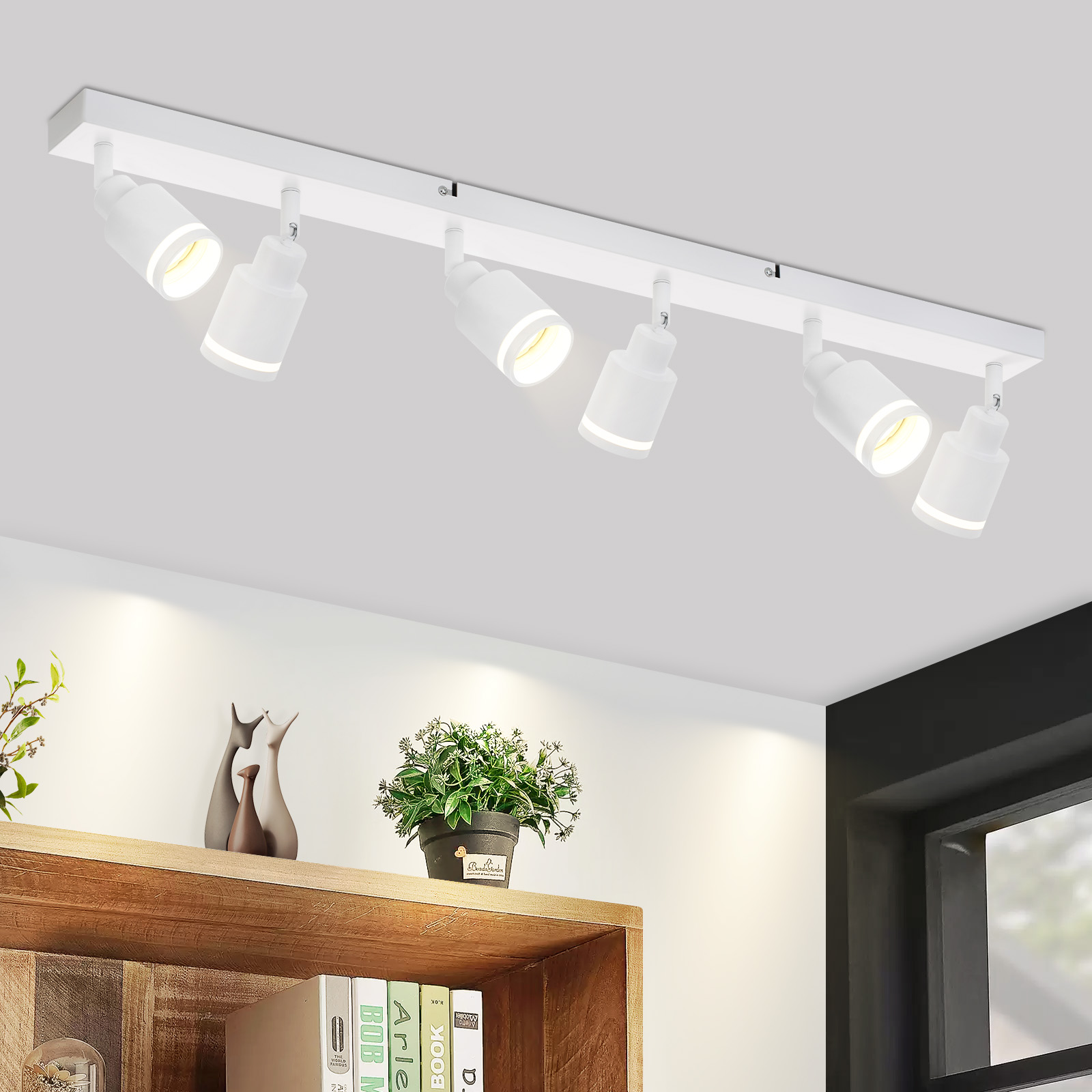 Luci a soffitto bianche con faretti regolabili, su un soffitto bianco. Sotto, una mensola in legno con decorazioni.