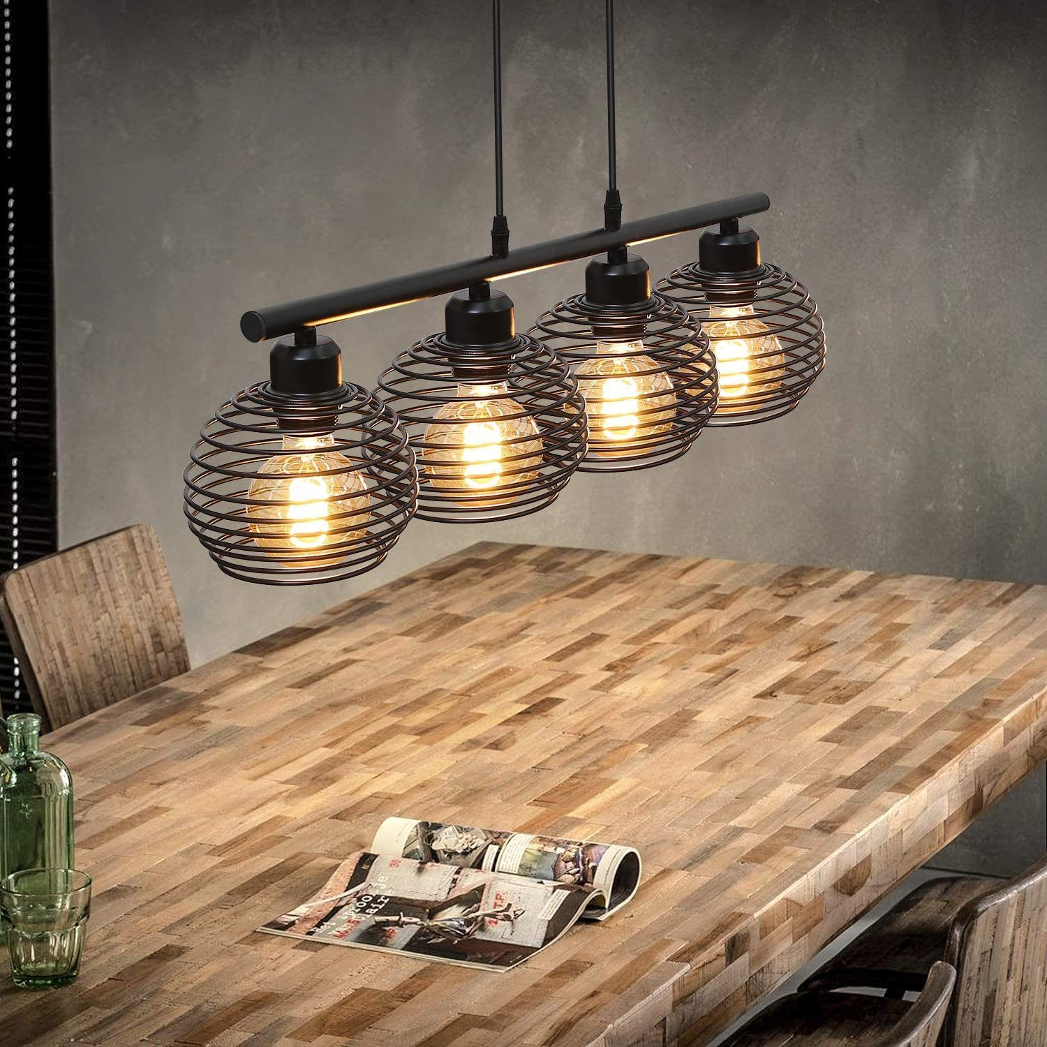 Esszimmer mit Holztisch und vier Pendelleuchten. Die Leuchten haben spiralförmige Metallschirme.