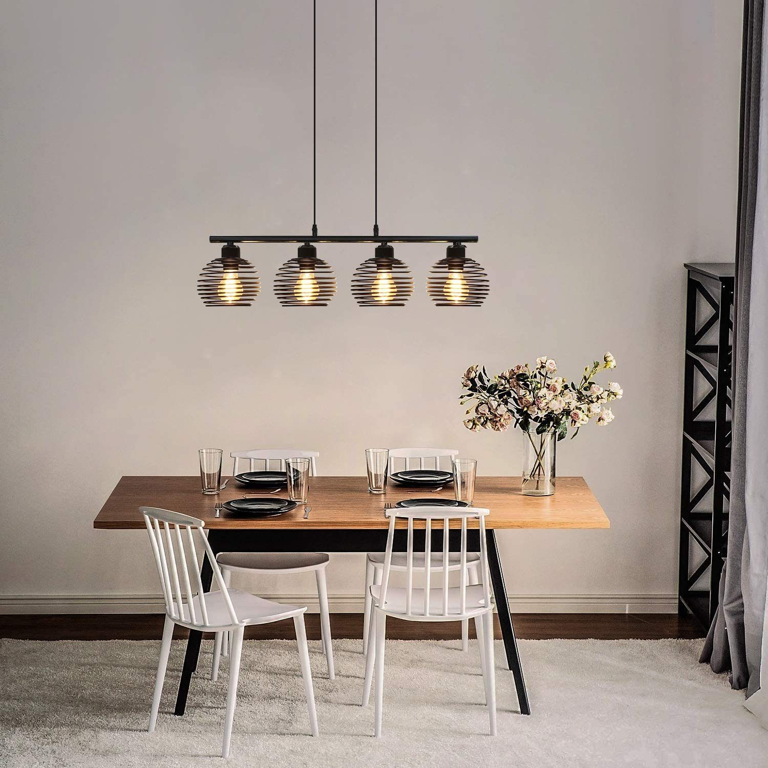 Esszimmer mit vier Pendelleuchten, einem Holztisch mit Tellern und Stühlen.
