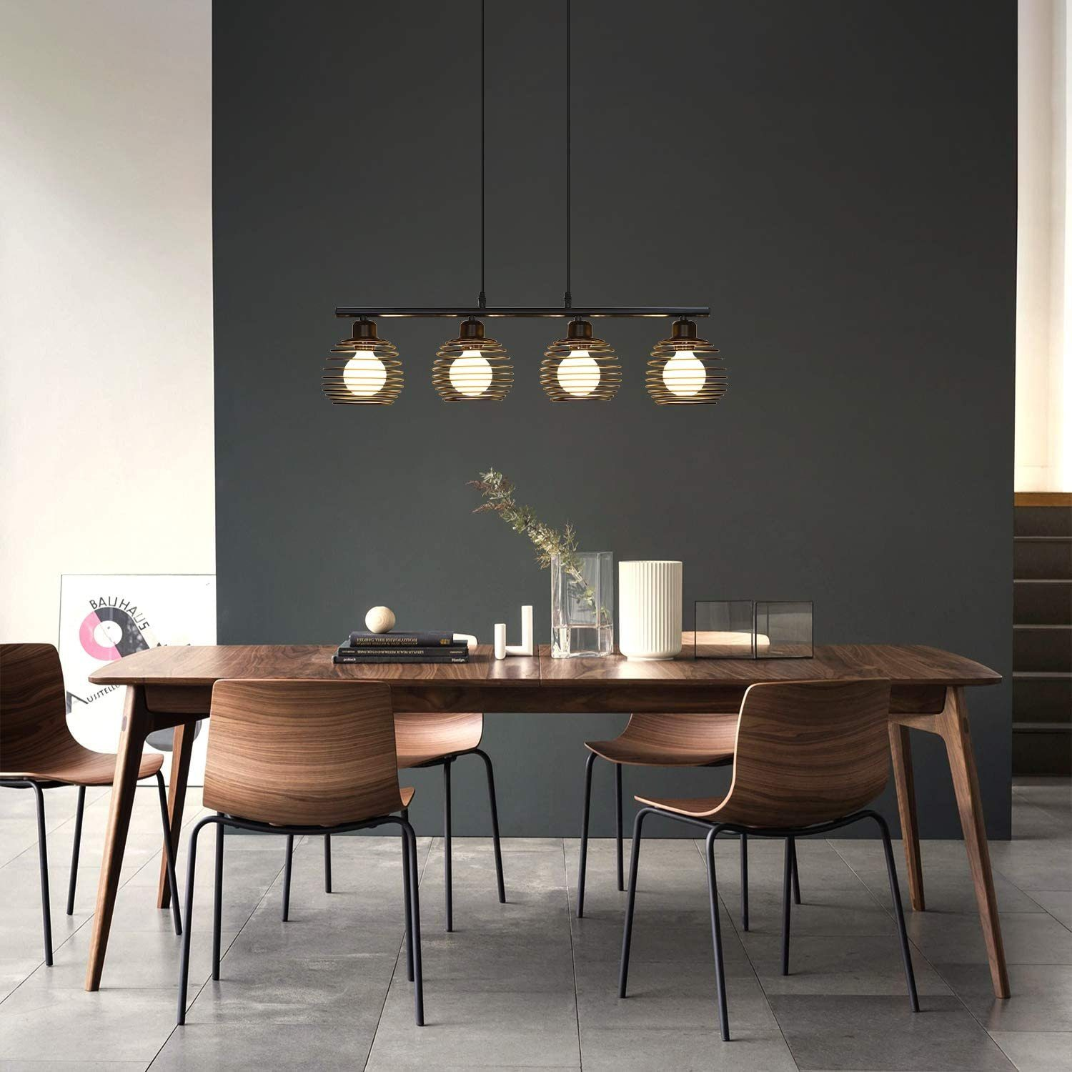 Ein Esszimmer mit einem langen Holztisch, Stühlen und einer schwarzen Pendelleuchte.