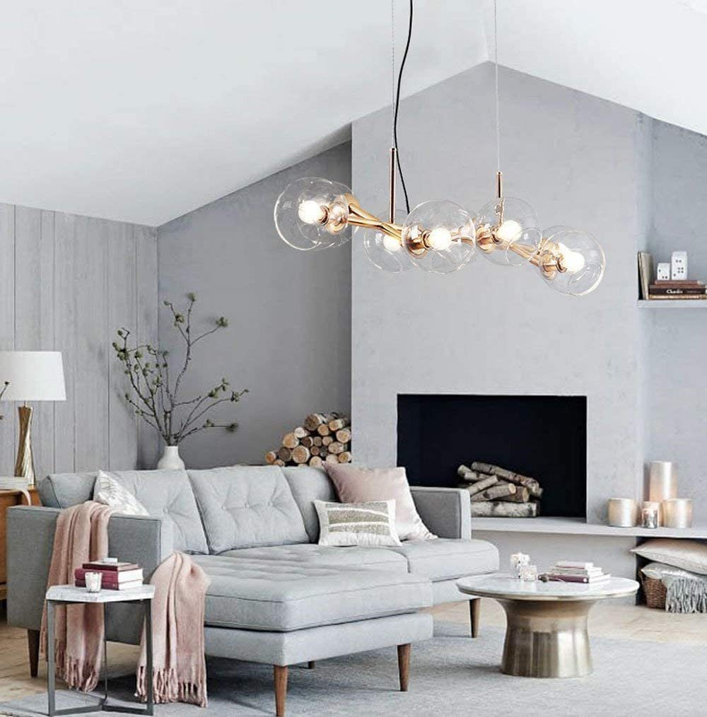 Wohnzimmer mit grauem Ecksofa, Kamin und moderner Kronleuchter mit mehreren Lichtern.