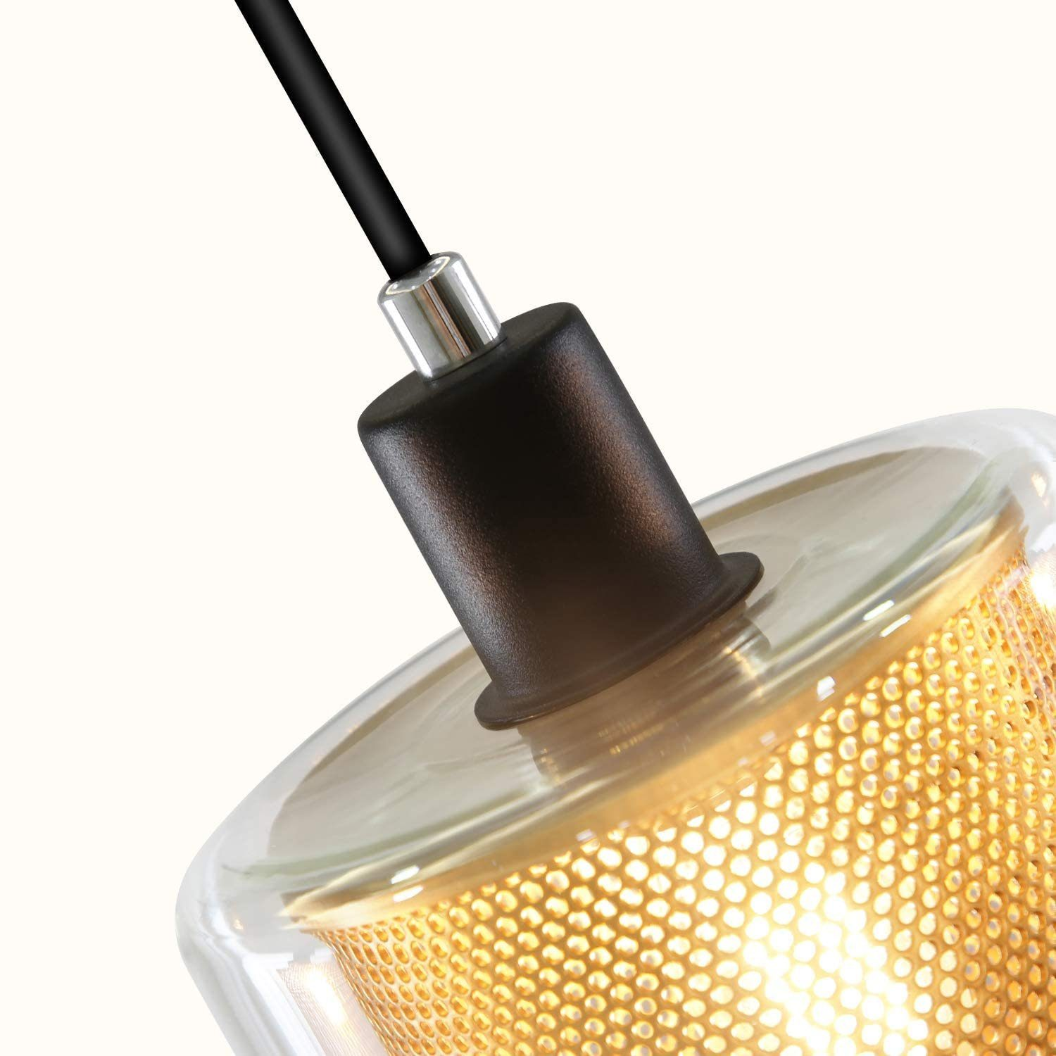 Nahaufnahme einer Pendelleuchte mit schwarzem Oberteil, Glasschirm und goldfarbenem Gitter innen.