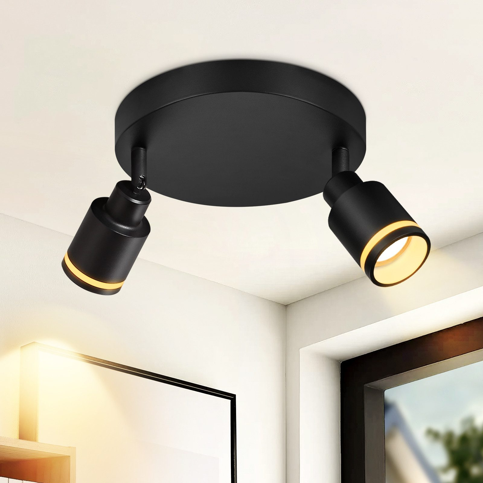 Due faretti neri su una base nera a soffitto, che illuminano un soffitto bianco e la luce sulla parete destra.