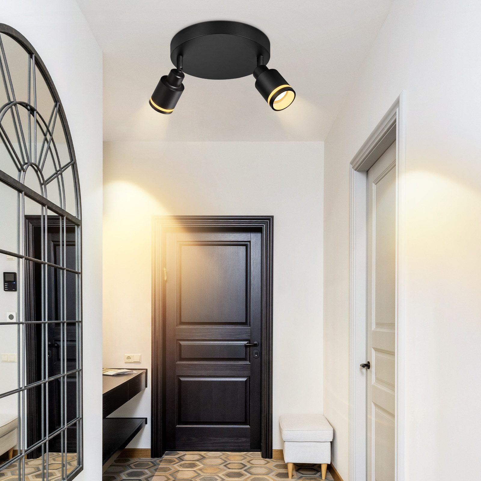 Corridoio con porta nera e due faretti a soffitto. Visibili uno specchio e una consolle.