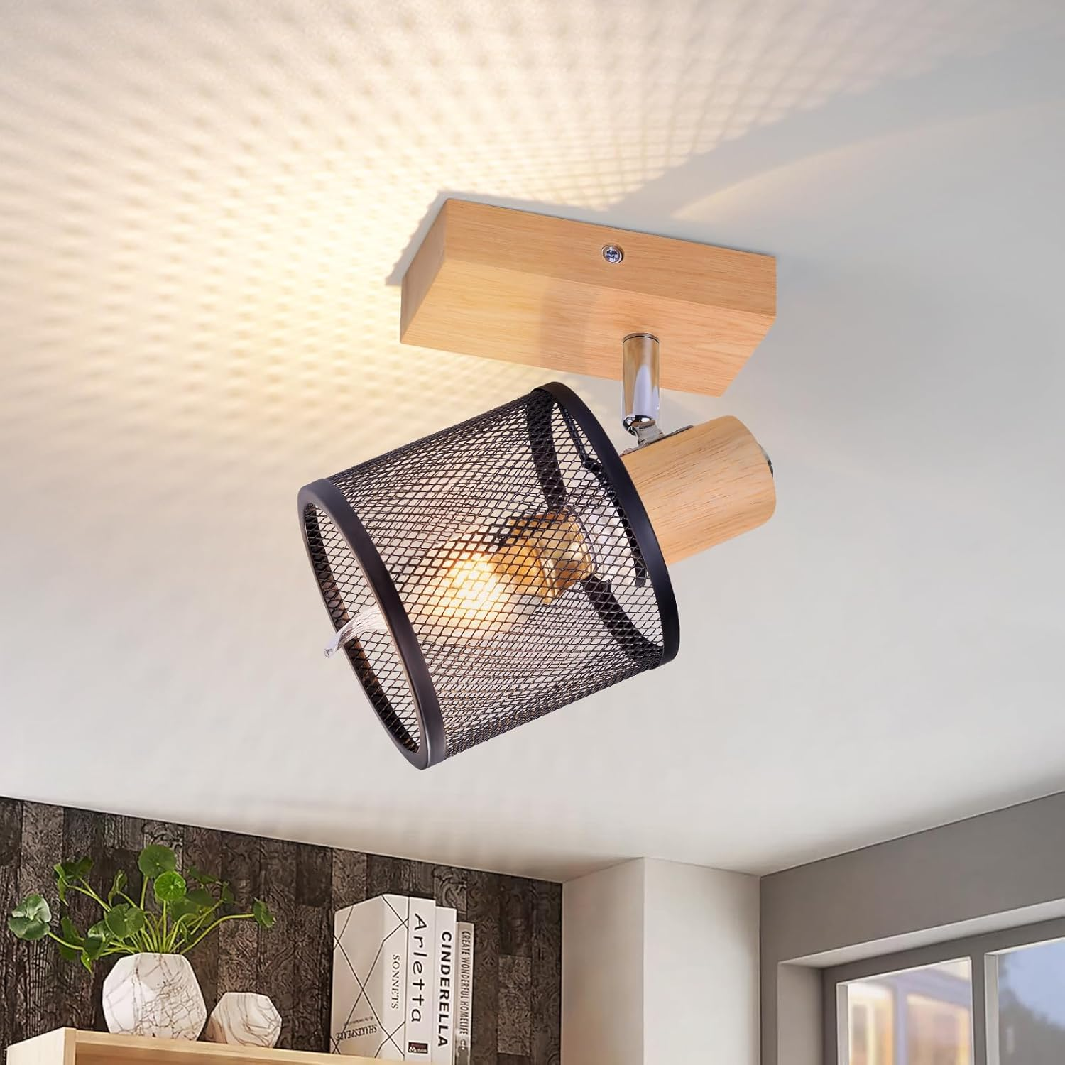 Un faretto a rete metallica nera è montato su un apparecchio a soffitto in legno chiaro. La luce è accesa.