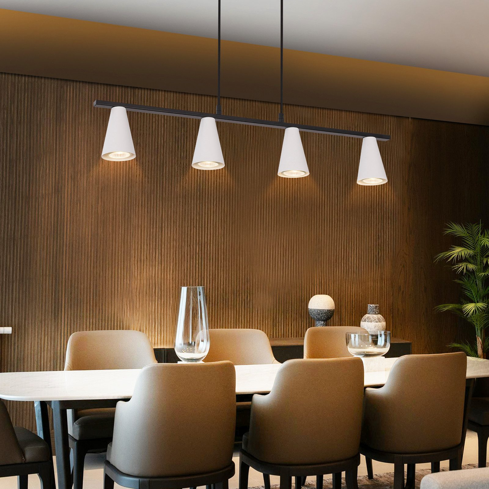 Esszimmer mit Holzwand und Tisch mit Stühlen. Über dem Tisch hängt eine Lampe.