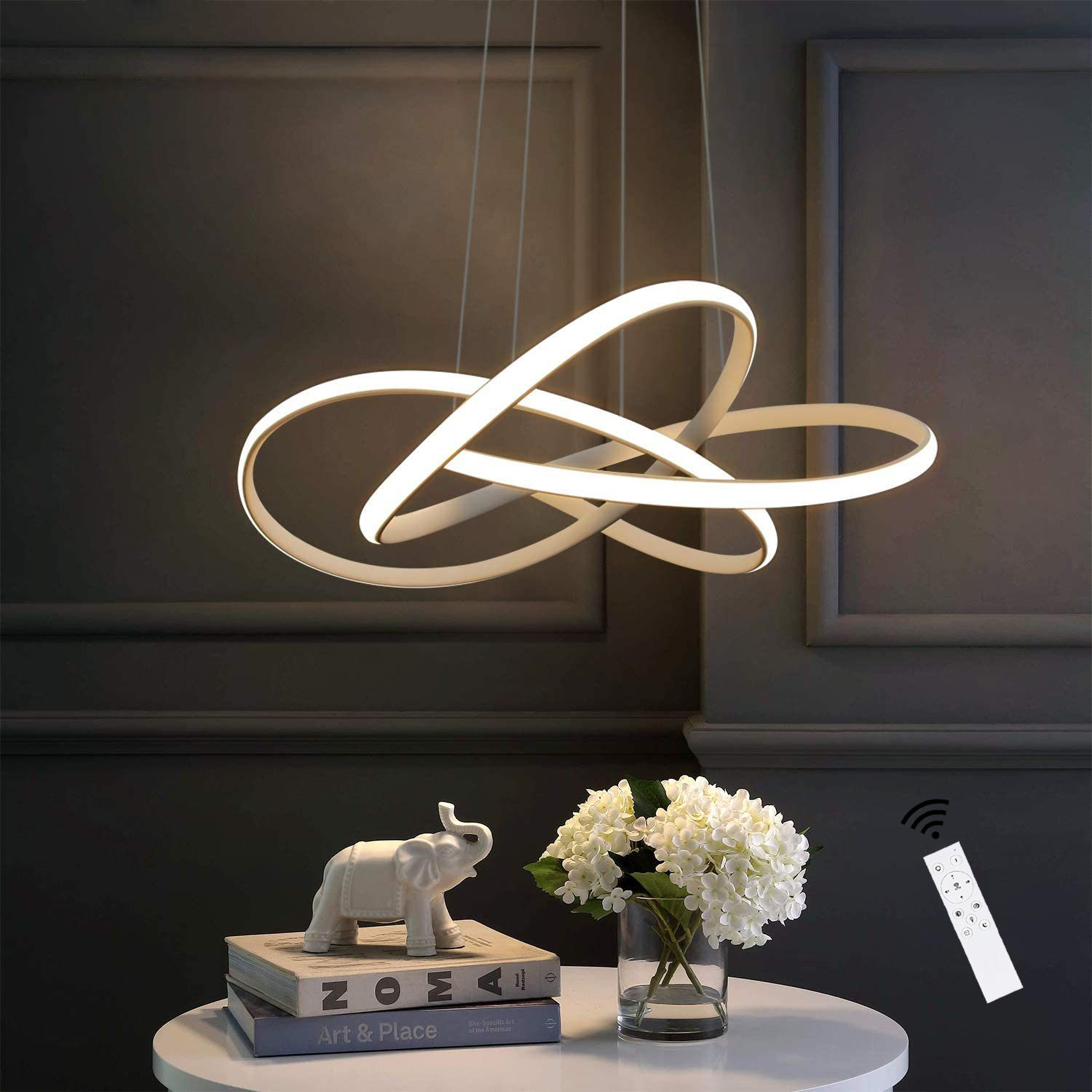Luz de techo blanca y abstracta con tres elementos curvos, colgada en una habitación con decoración.