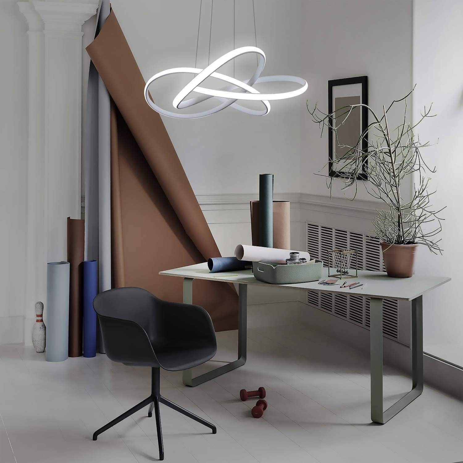 Habitación moderna con luz colgante. Mesa, silla y varios materiales de arte. Paredes blancas.