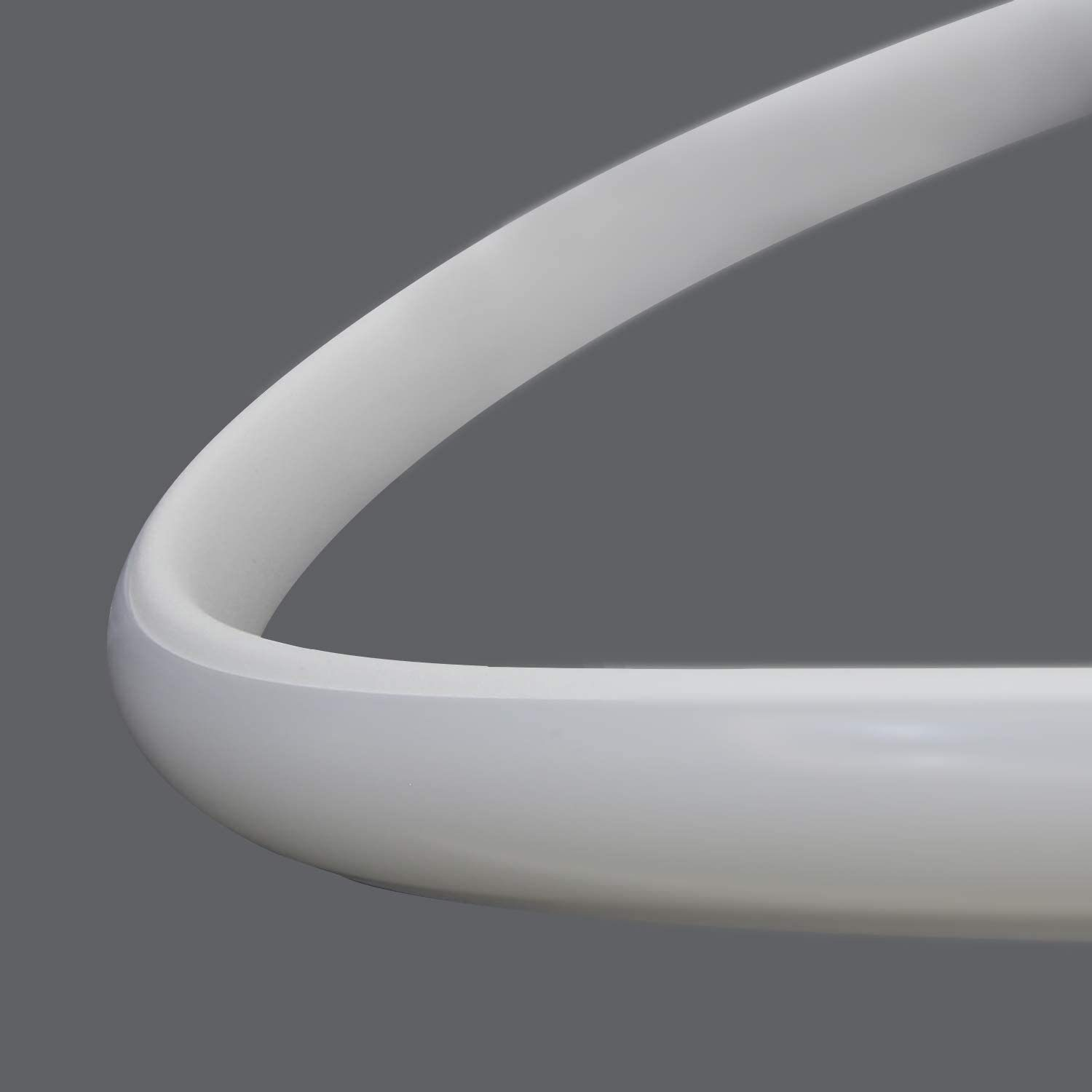 Primer plano de una lámpara blanca y curva sobre un fondo gris.