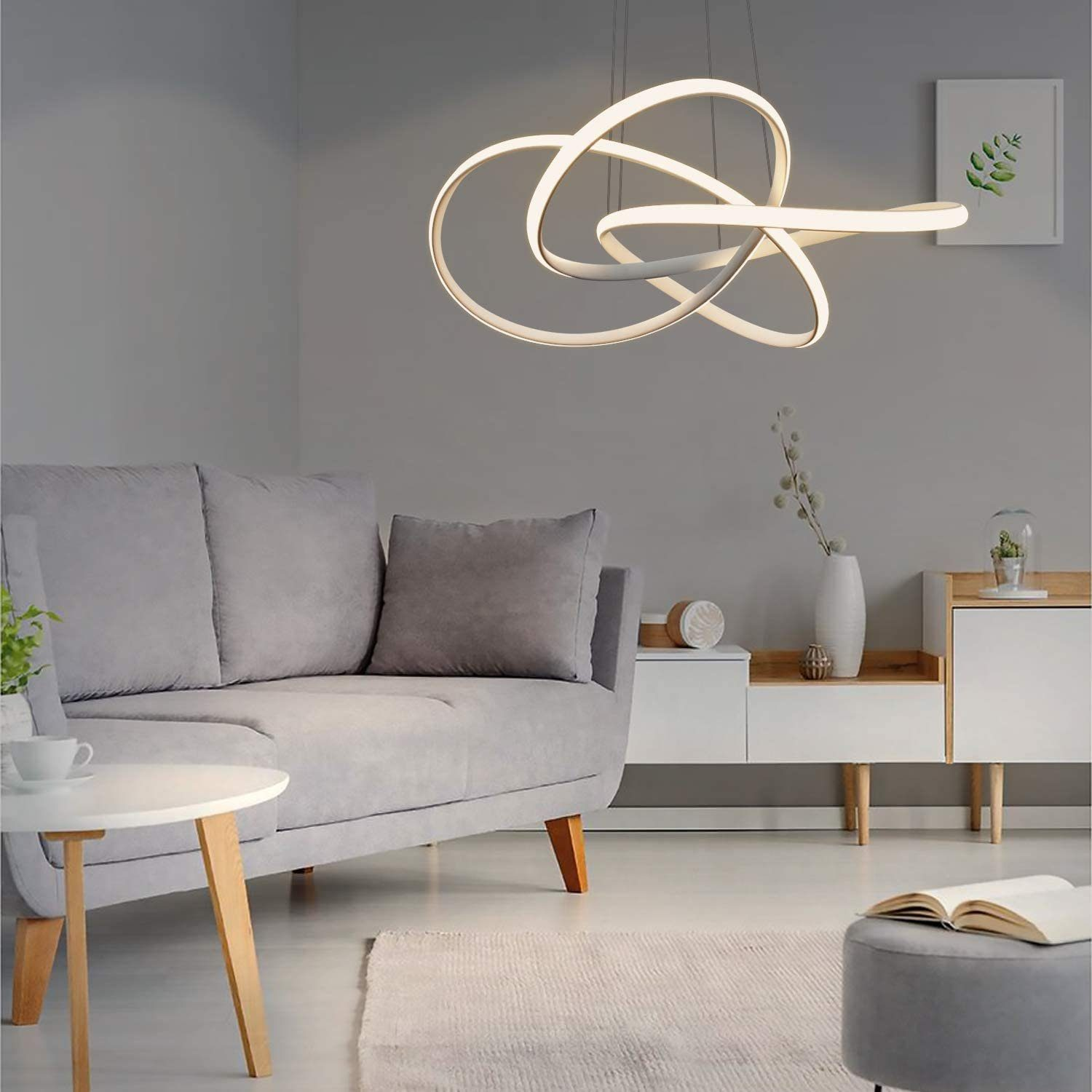 Luz de techo blanca y abstracta en un salón con muebles, sofá y mesa auxiliar.