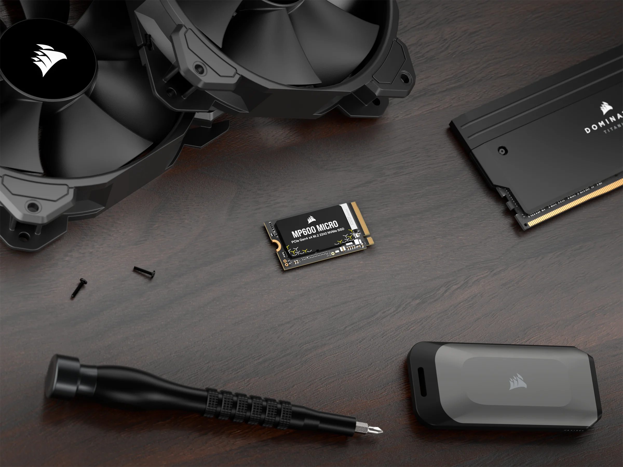 Elementy komputera: wentylatory, dysk SSD, śrubokręt i mała obudowa. Ciemne tło.