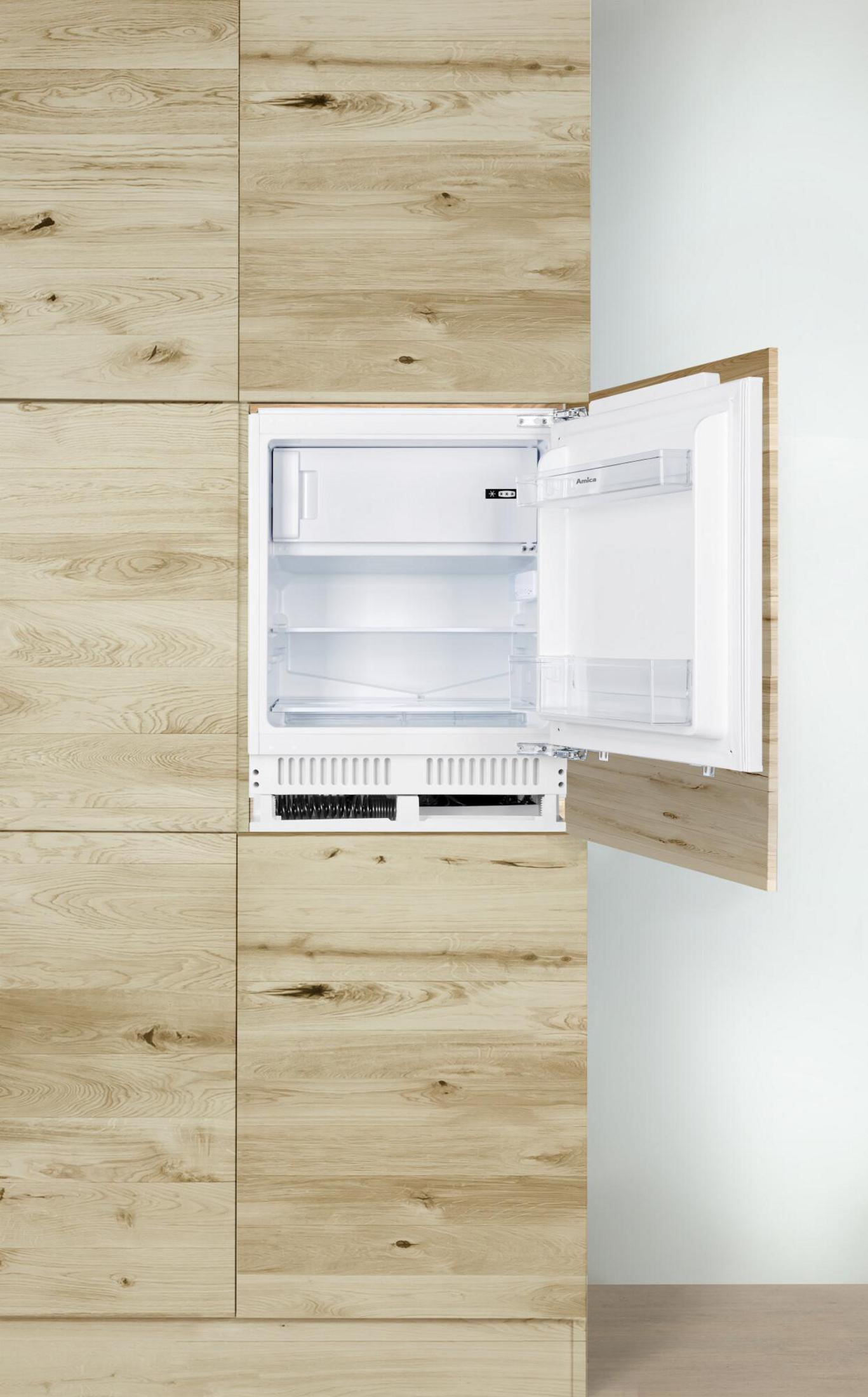 Ein eingebauter Kühlschrank mit offener Tür. Die Holzverkleidung an der Wand.