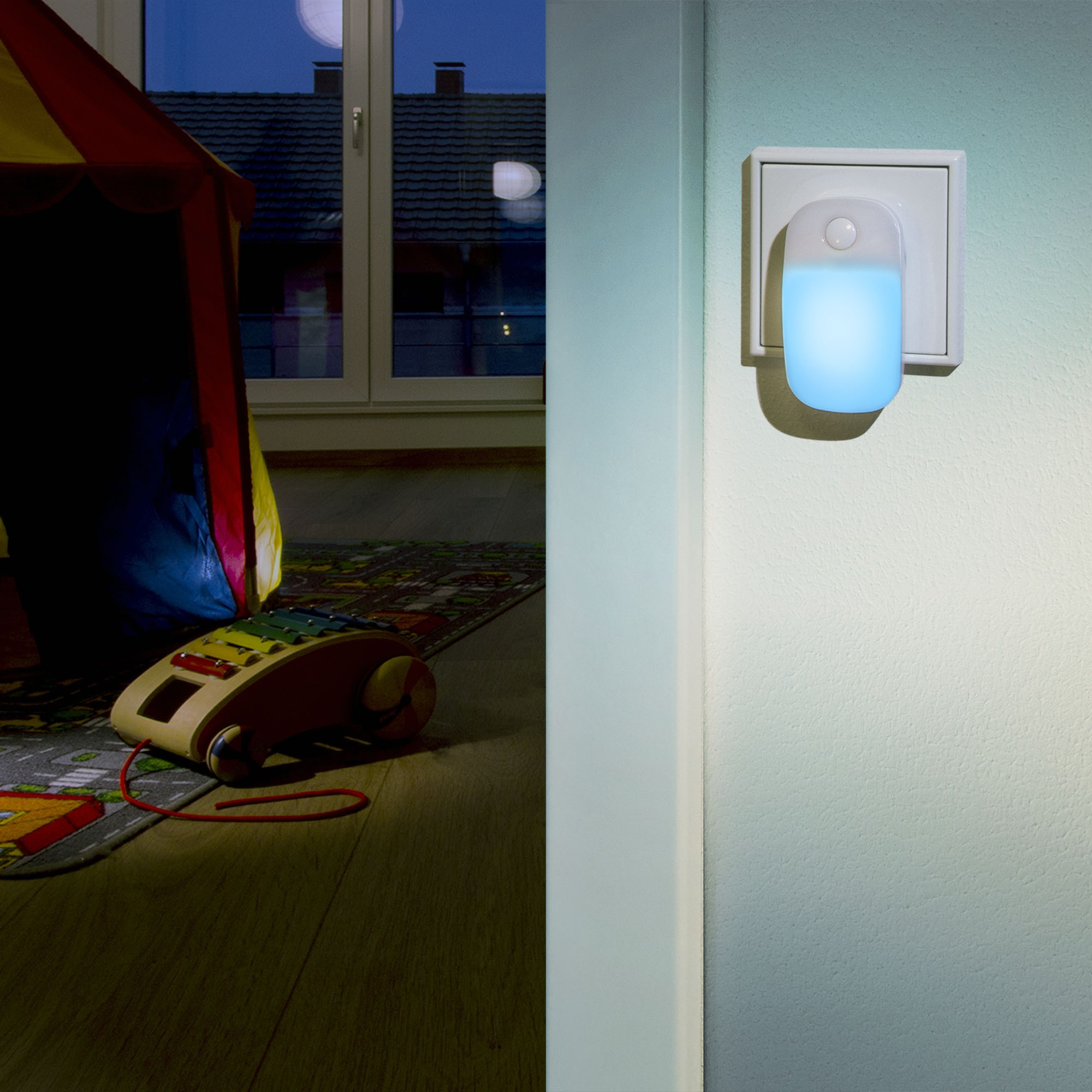 Ein blaues Nachtlicht ist in eine Wand gesteckt. Ein Spielzimmer hat ein Zelt und ein Xylophon.