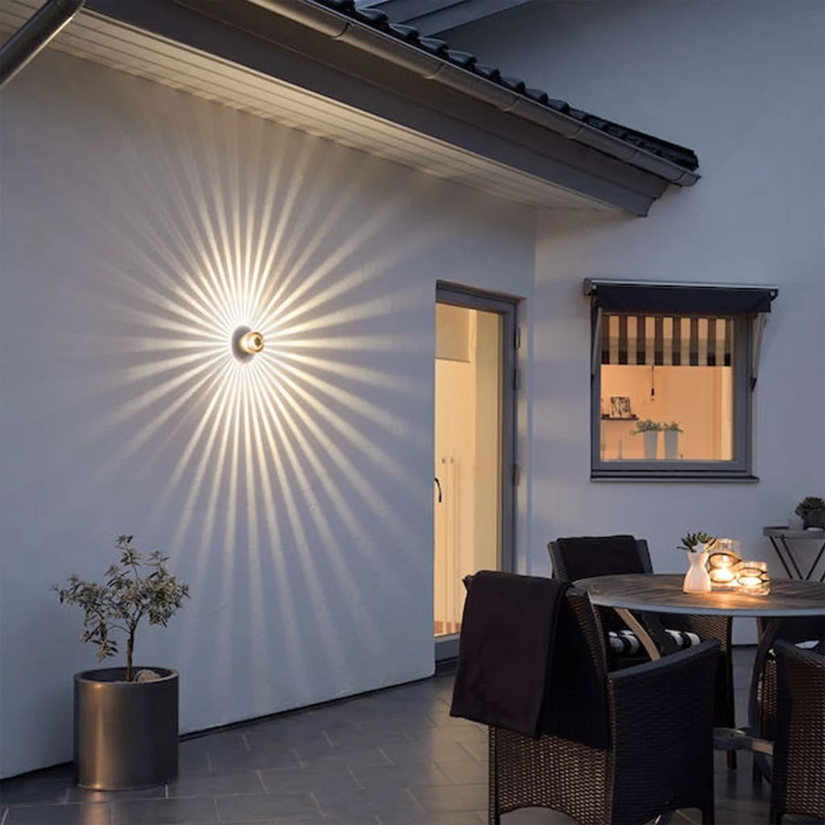 Esterno di una casa, illuminato con luci a parete che creano un motivo di luce radiante.