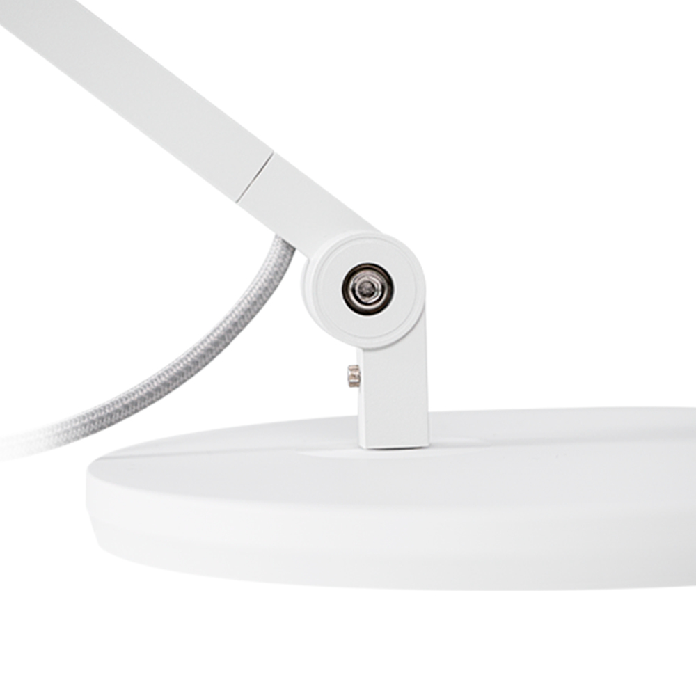 Zbliżenie na białą podstawę lampy biurkowej i ramię podporowe. Ramię jest mocowane śrubą.