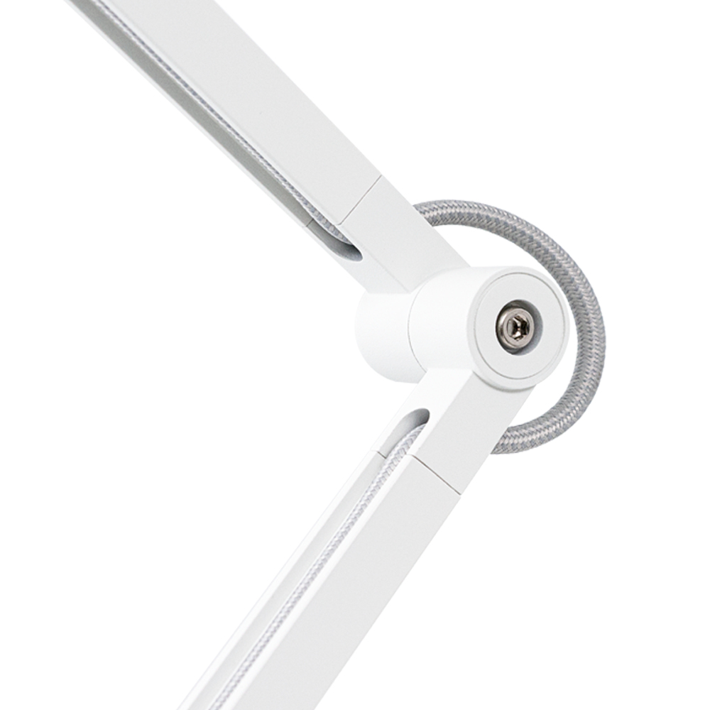 Zbliżenie białego przegubu lampy biurkowej. Szary przewód jest podłączony do przegubu.