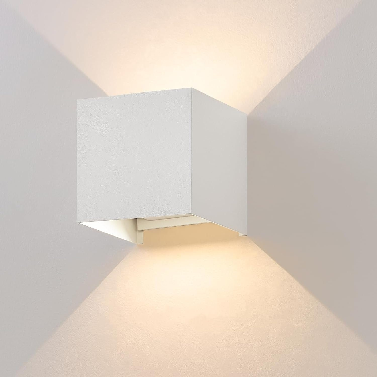 Lampada da parete bianca a forma di cubo, che proietta la luce verso l'alto e verso il basso.