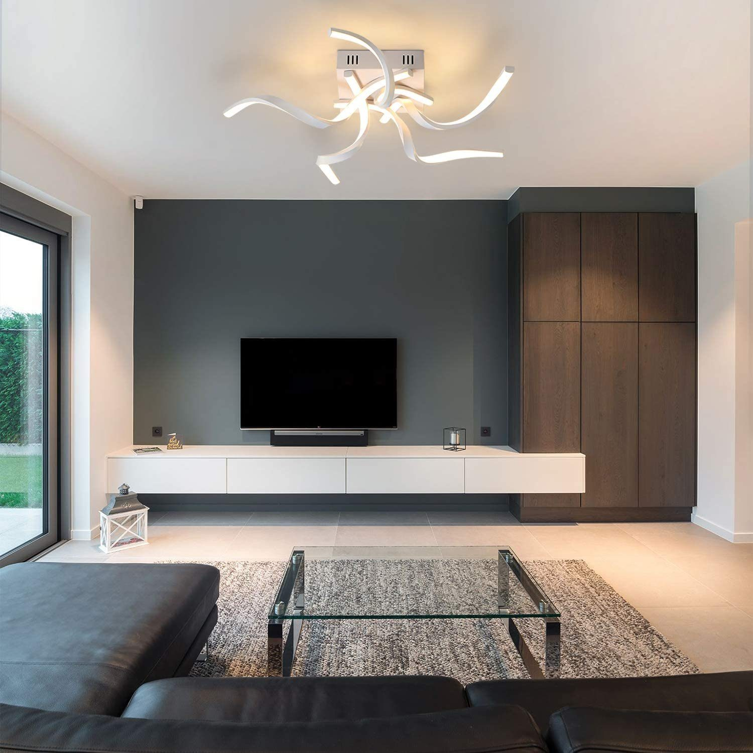 Ein Wohnzimmer mit weißer Deckenleuchte, Fernseher und dunkelgrauer Wand. Dunkle Holzschränke und Sofa.
