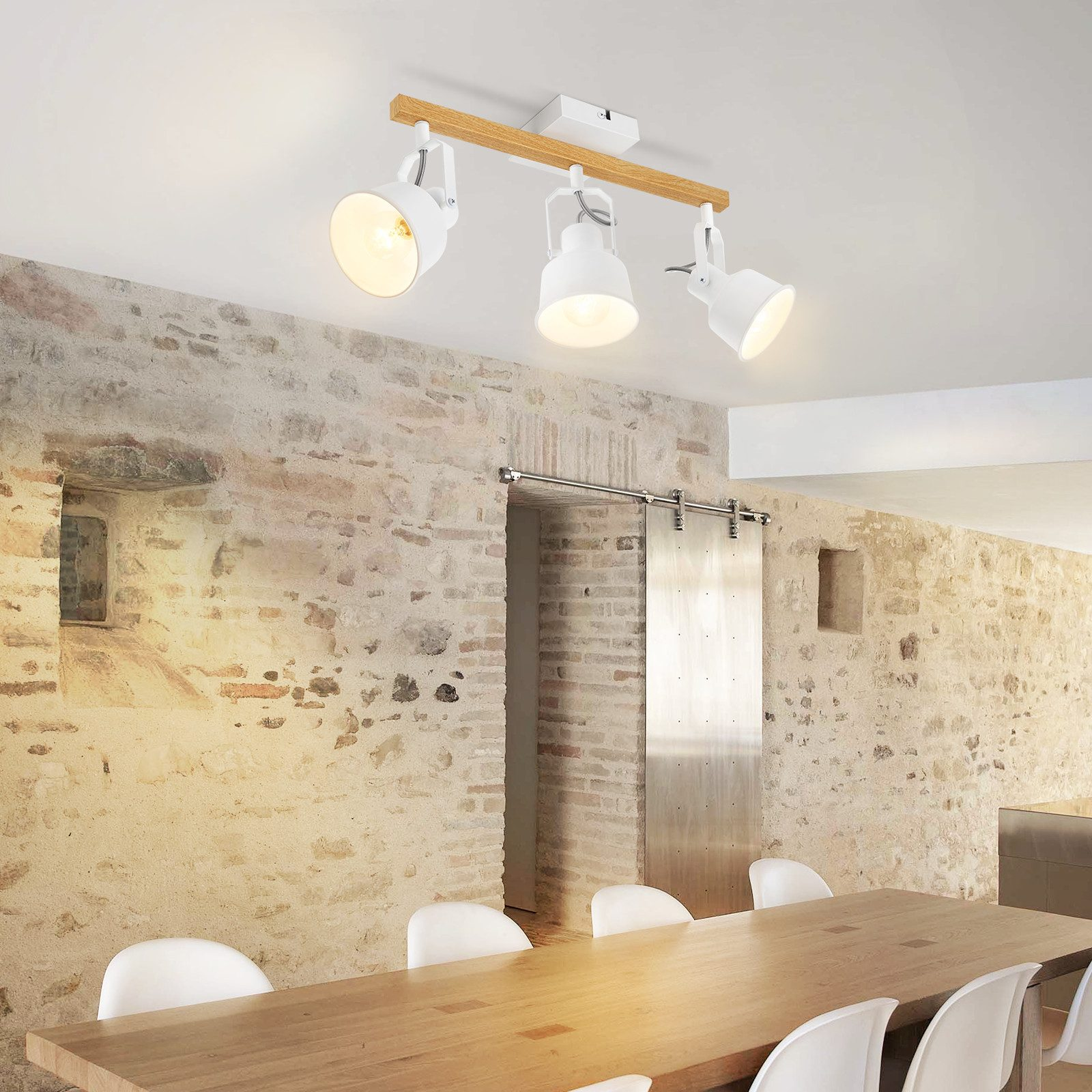 Jadalnia ze stołem drewnianym, białymi krzesłami i trzema białymi reflektorami.