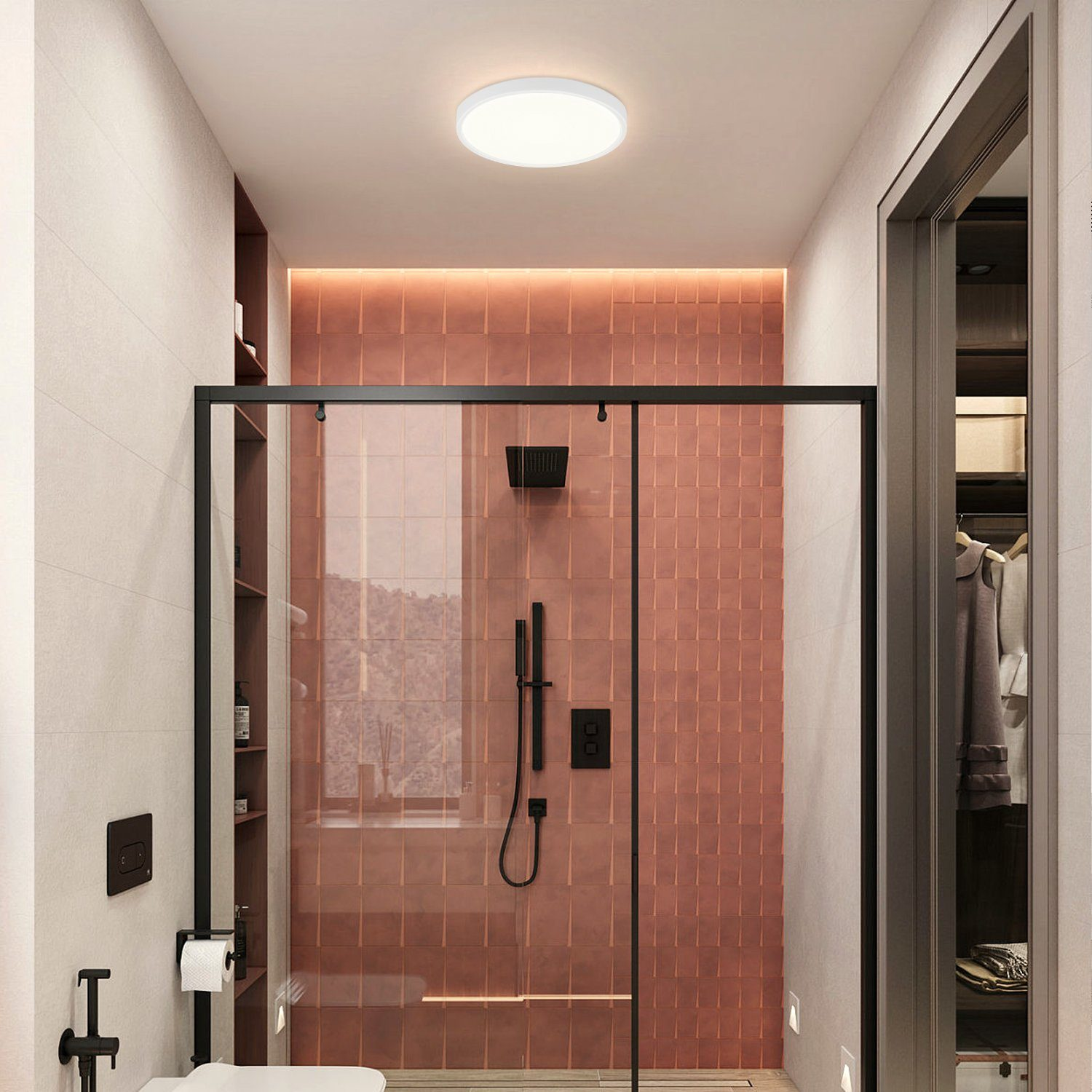 Ein Badezimmer mit Dusche. Die Wände sind rosa gefliest. Ein Duschkopf und schwarze Armaturen sind sichtbar.