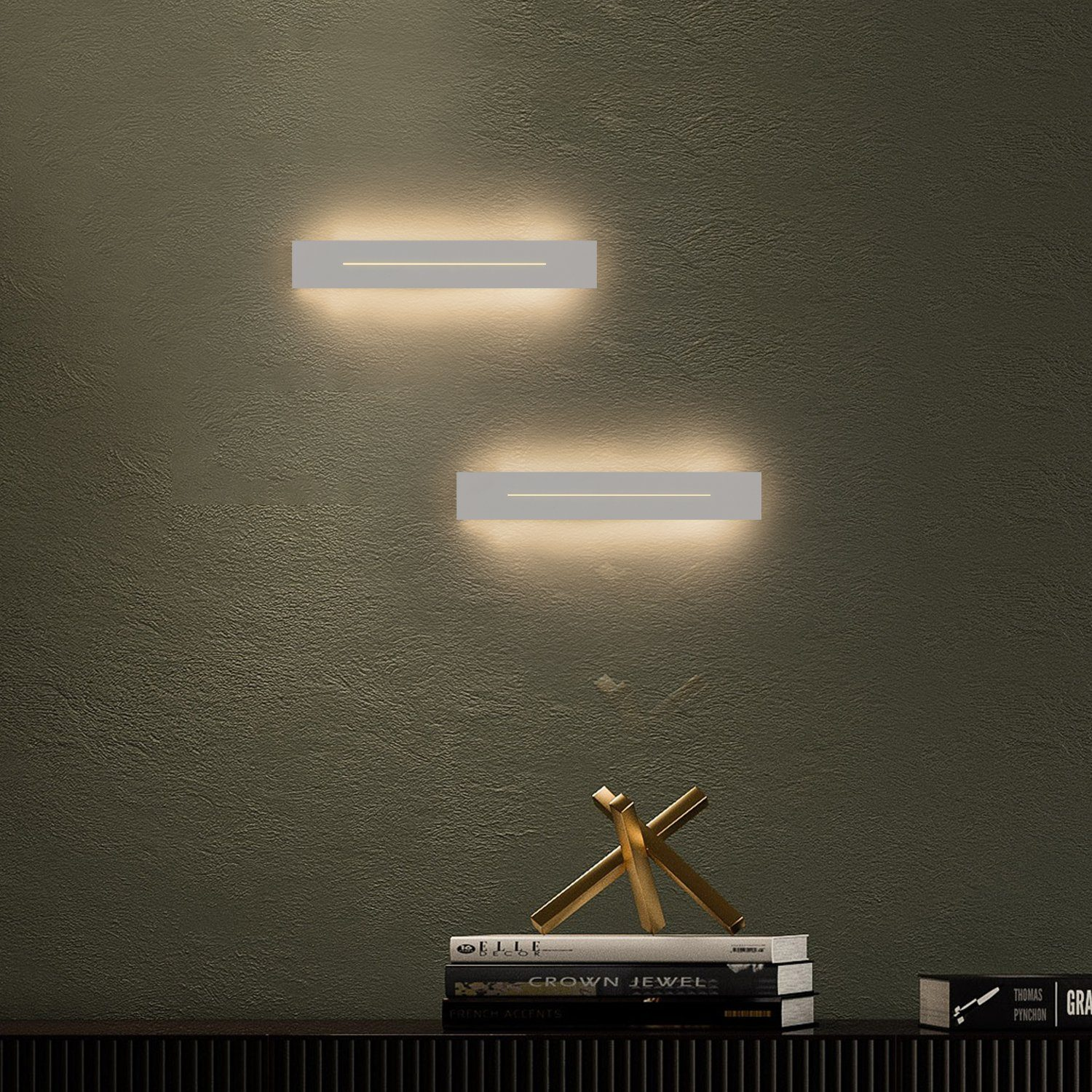 Due luci da parete che emettono luce. Sotto ci sono libri e un oggetto decorativo.
