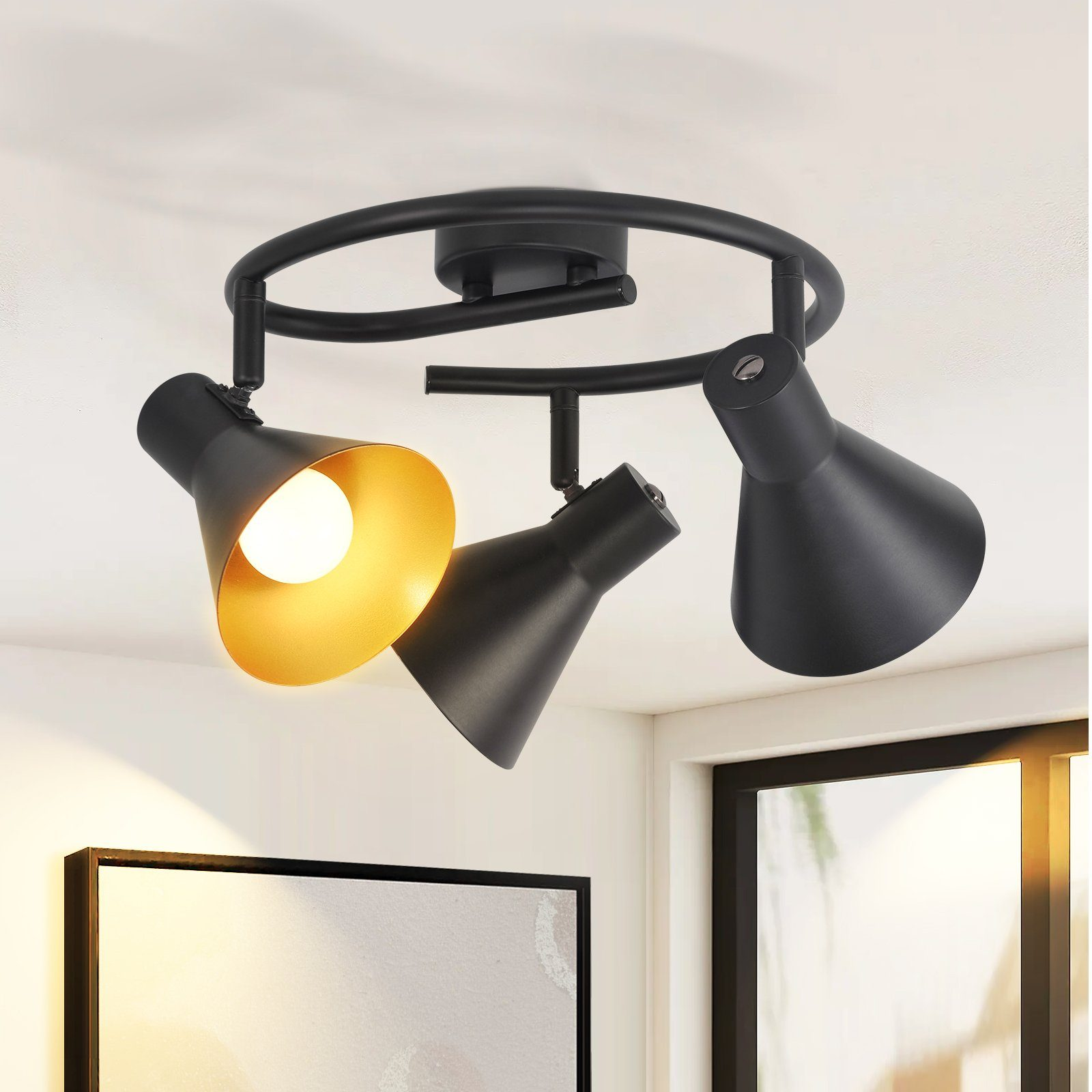 Faretto da soffitto nero con tre lampade regolabili, interno dorato, su un soffitto bianco.