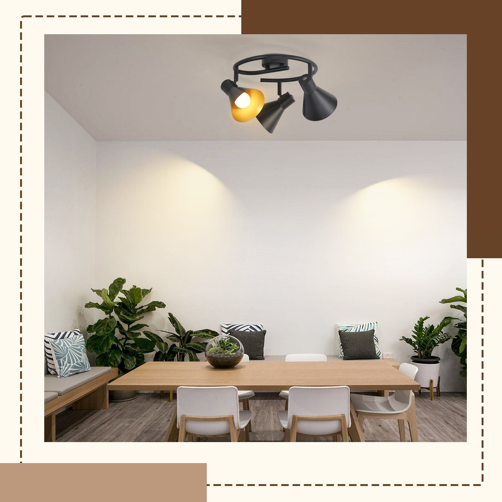 Luci a soffitto moderne sopra un tavolo di legno, con sedie e piante visibili, in una stanza bianca.