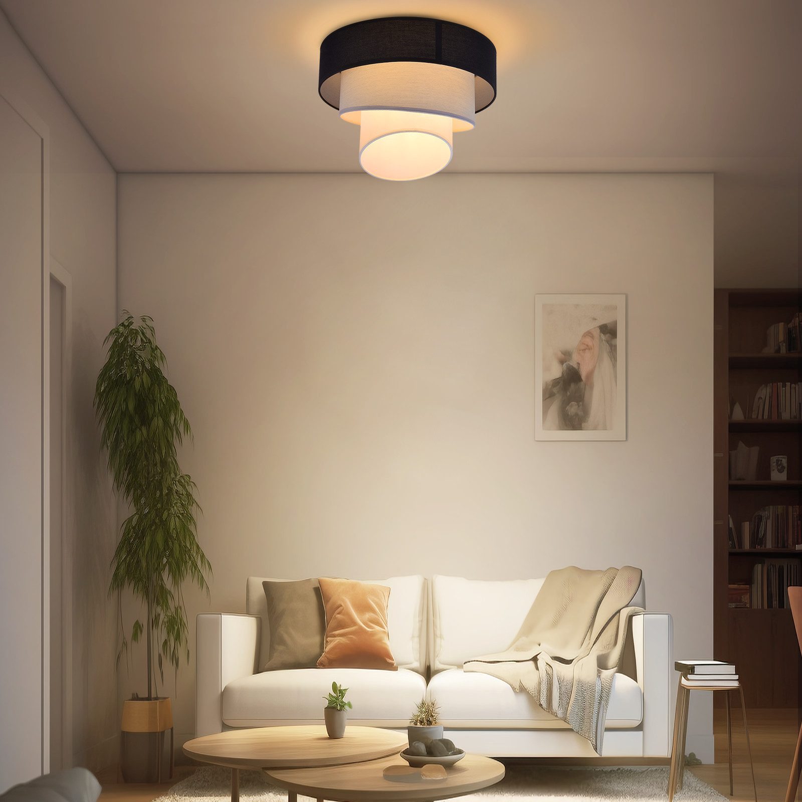 Soggiorno con lampada da soffitto, divano bianco, tavolini e una pianta.