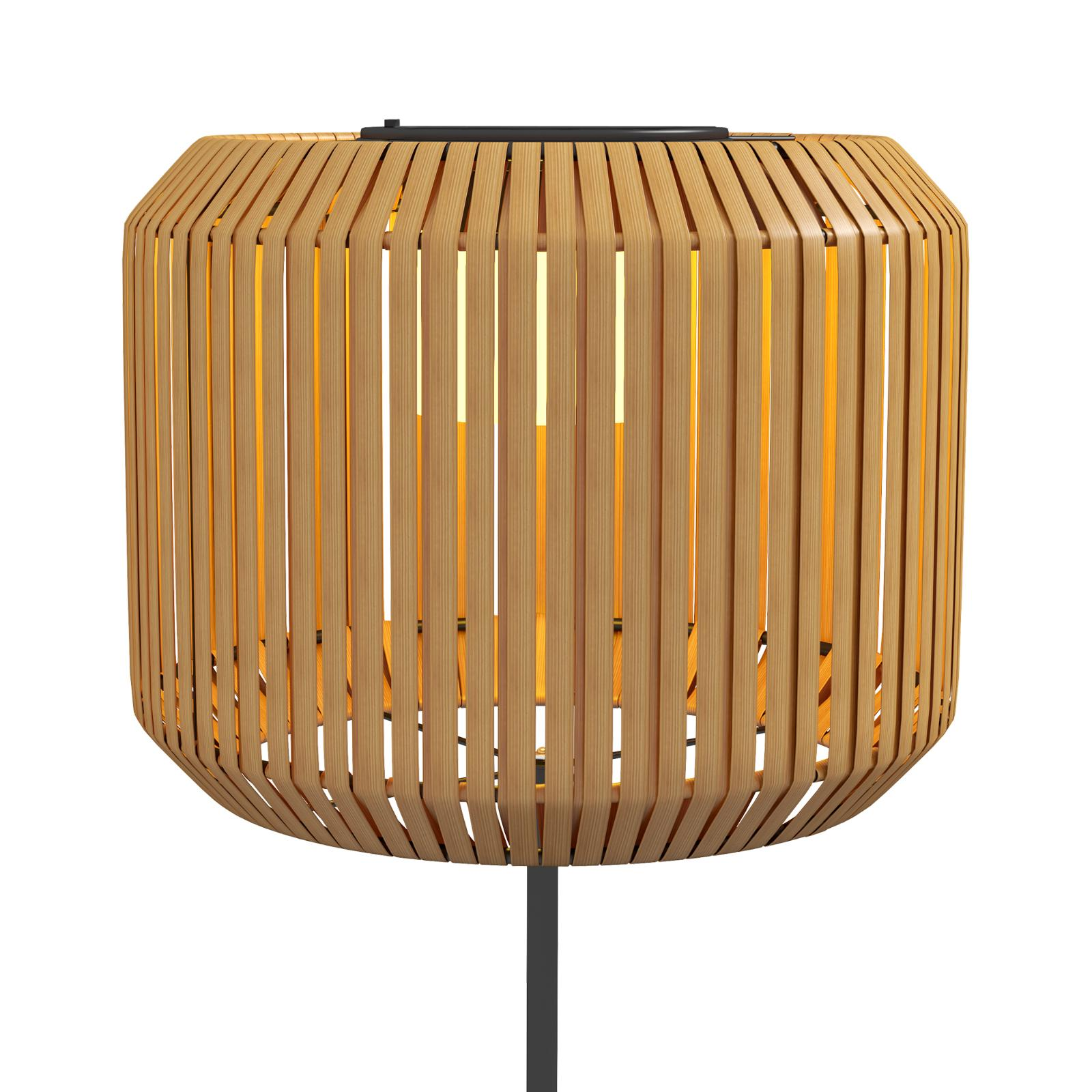 Eine Holzlampe mit Licht im Inneren. Die Lampe ist hoch und hat eine zylindrische Form.