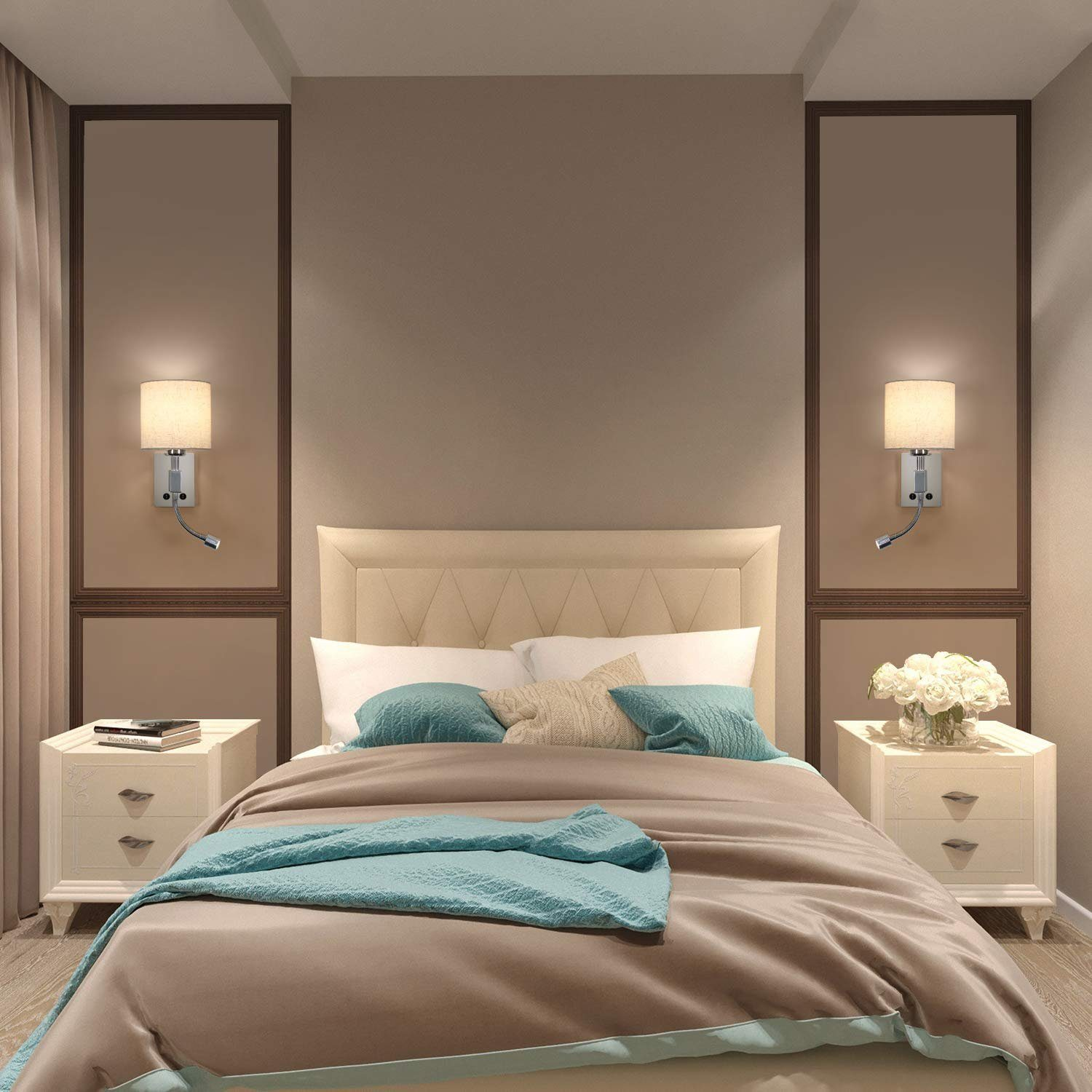 Ein Schlafzimmer mit beigem Bett, zwei Nachttischen und Wandlampen. Das Bett hat blaue und beige Bettwäsche.