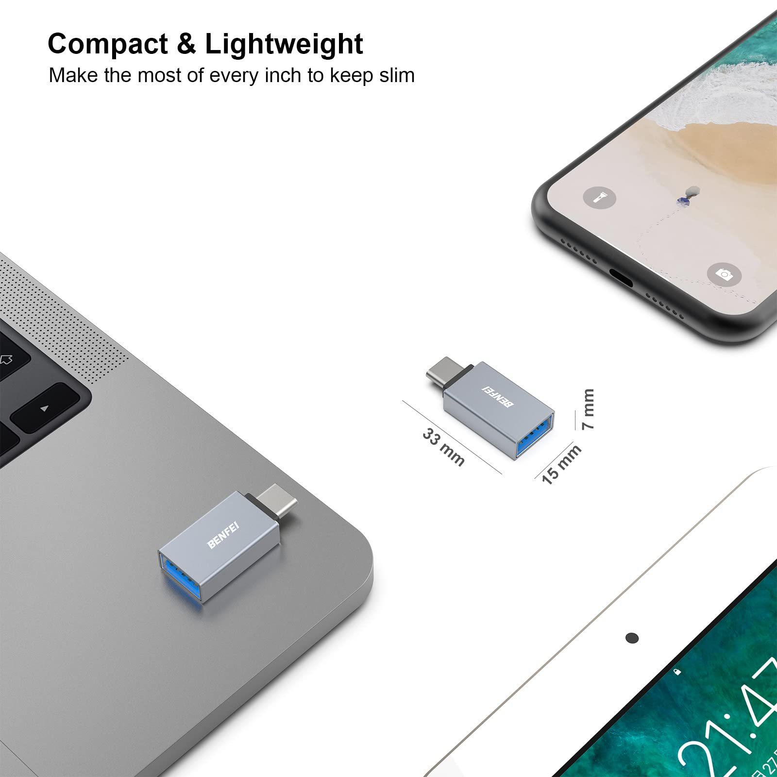 Ein silberner USB-C-Adapter neben einem Laptop, Tablet und Telefon.