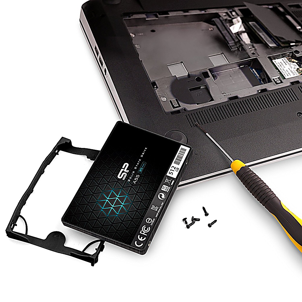 Eine SSD neben einem Laptop mit Schrauben und einem Schraubendreher. Die SSD ist schwarz und hat ein blaues Muster.