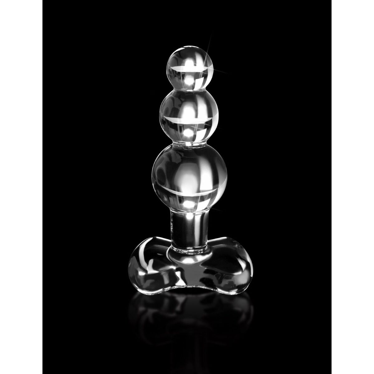 Tapón anal de vidrio transparente con tres esferas apiladas sobre una base, fondo negro.