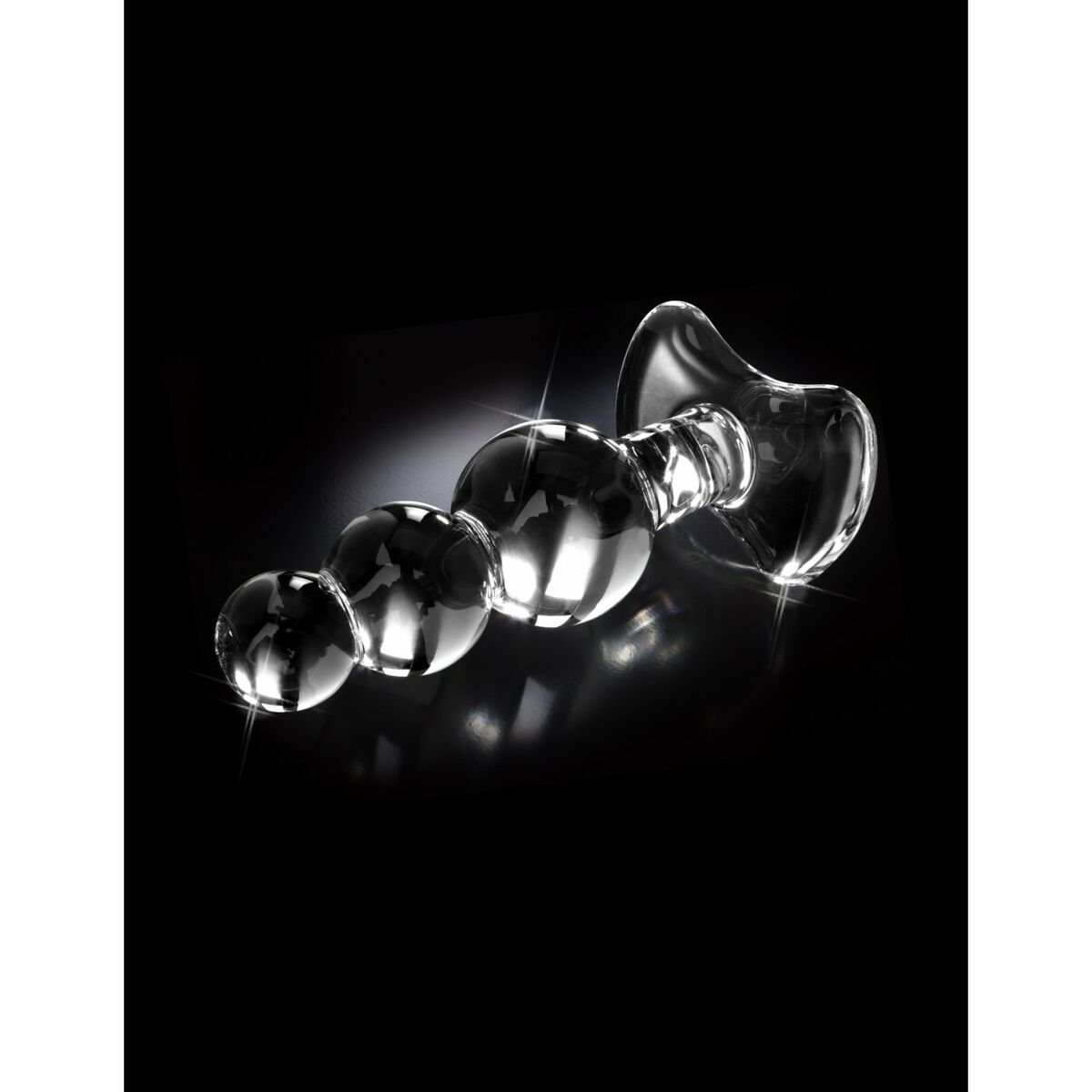 Tapón anal de vidrio transparente con tres esferas y una base ensanchada, fondo negro.