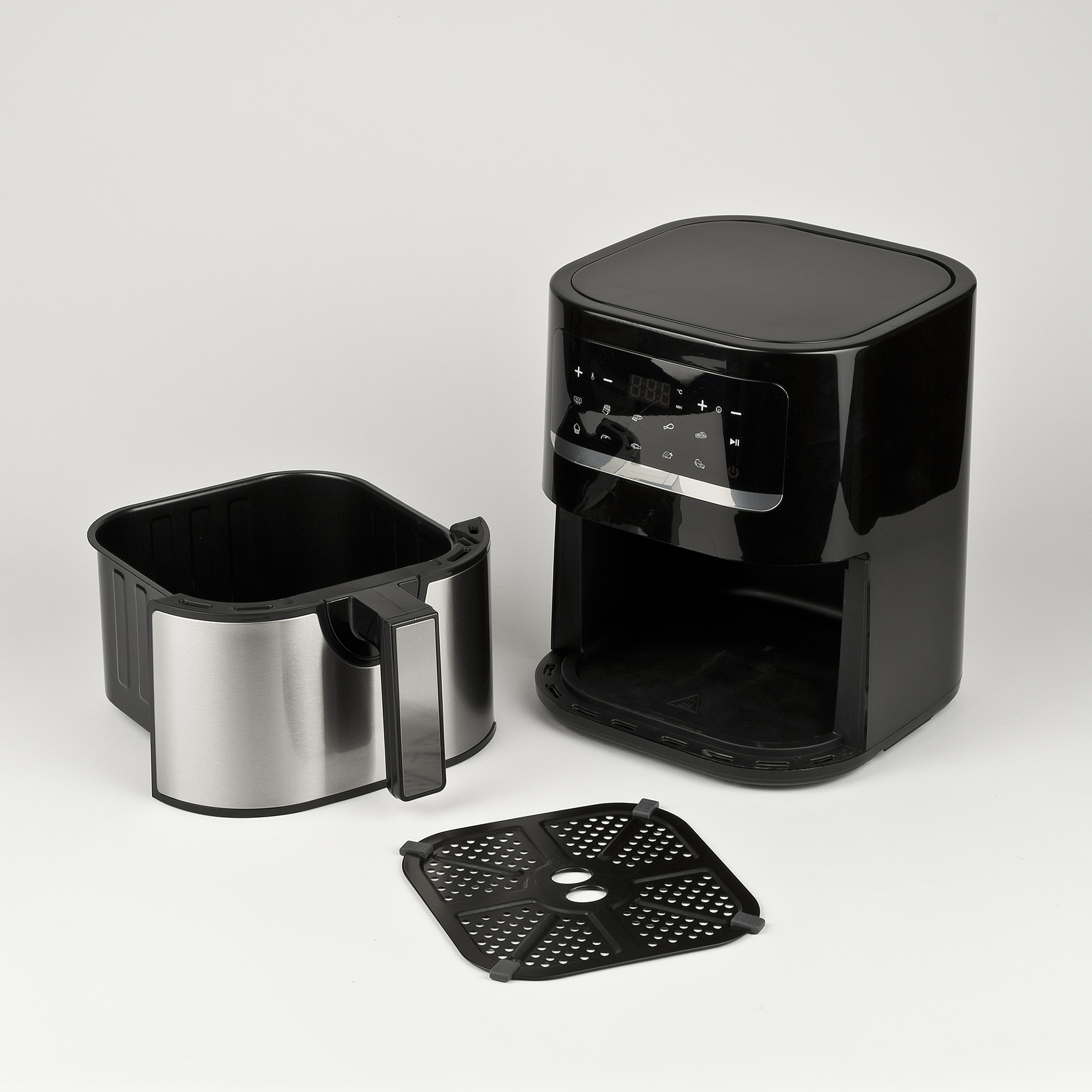 Zwarte airfryer gedemonteerd, mand, grillplaat en behuizing. 'Girmi' logo zichtbaar op wit oppervlak.