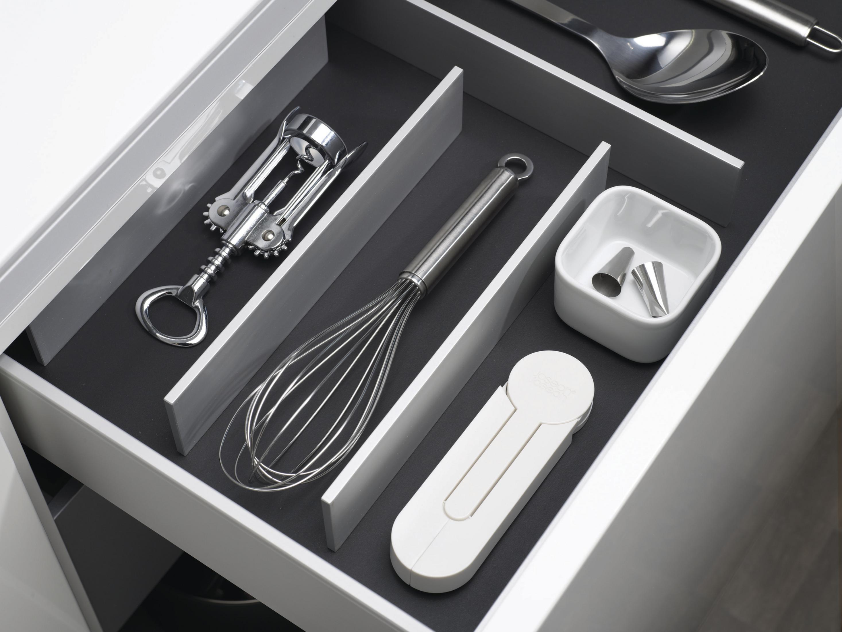 Un cassetto contenente utensili da cucina come un cavatappi, una frusta e altri strumenti bianchi.