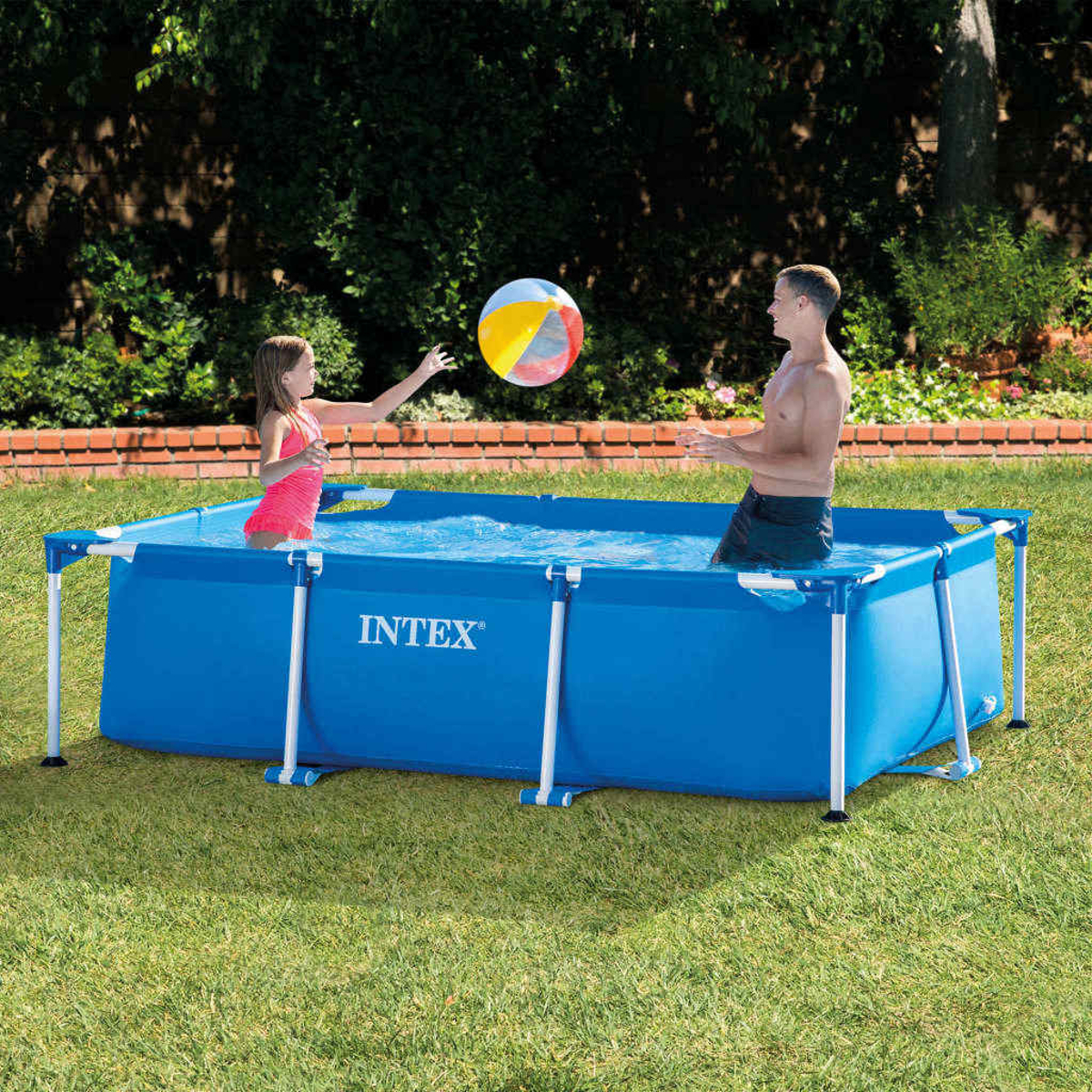Ein blaues rechteckiges Becken mit einem Mädchen und einem Mann, die mit einem Ball spielen, sonnige Umgebung.