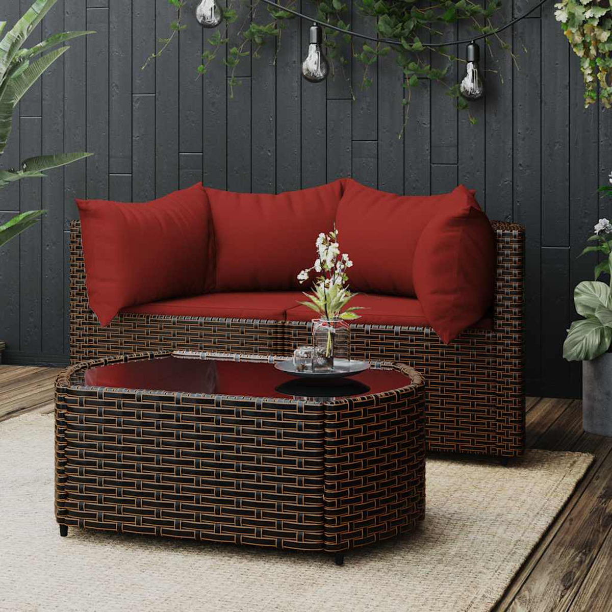 Rattan-Sofa und Couchtisch mit roten Kissen, Szene im Freien.