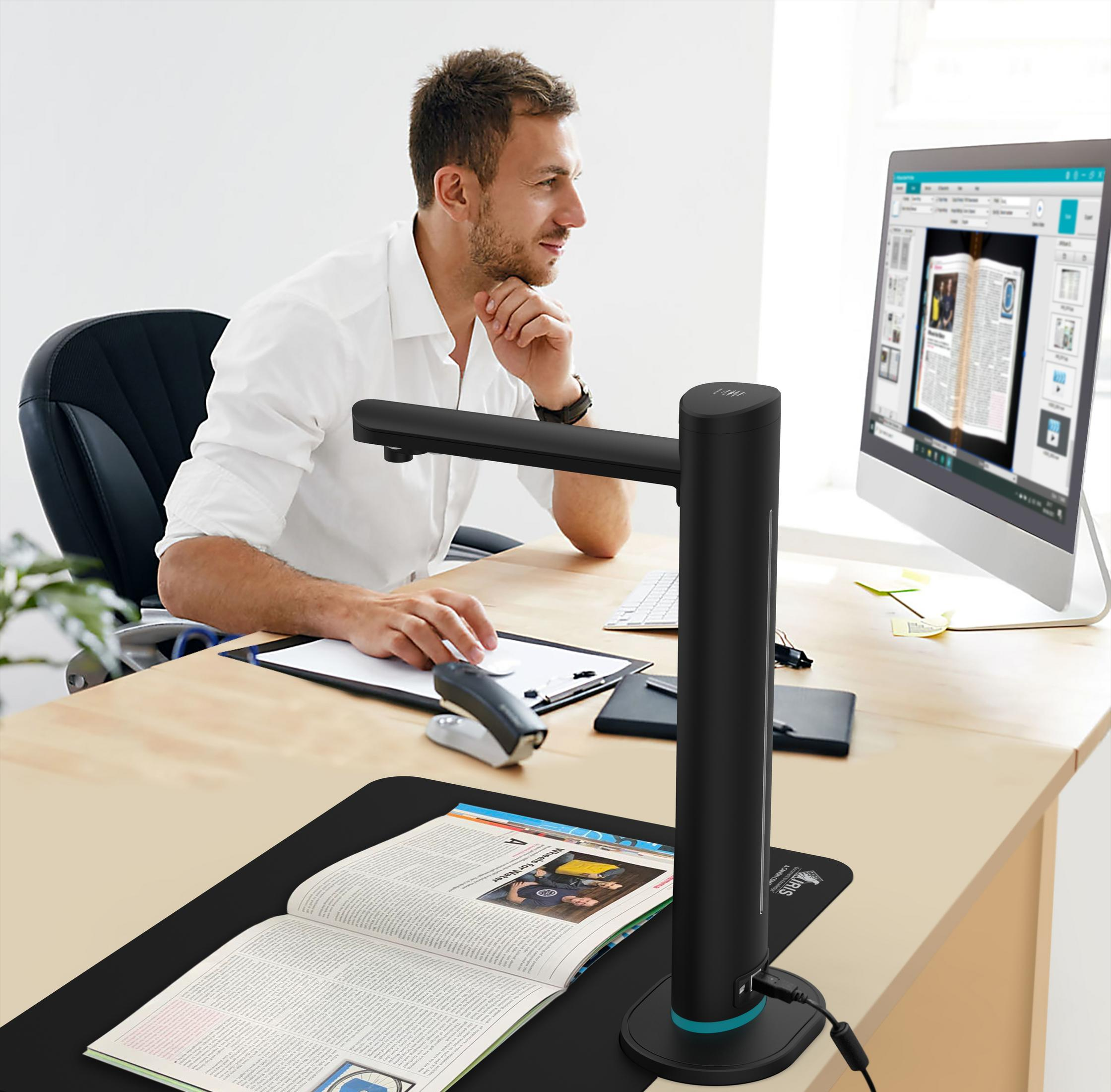 Hombre escaneando un libro con un escáner, monitor en el escritorio.