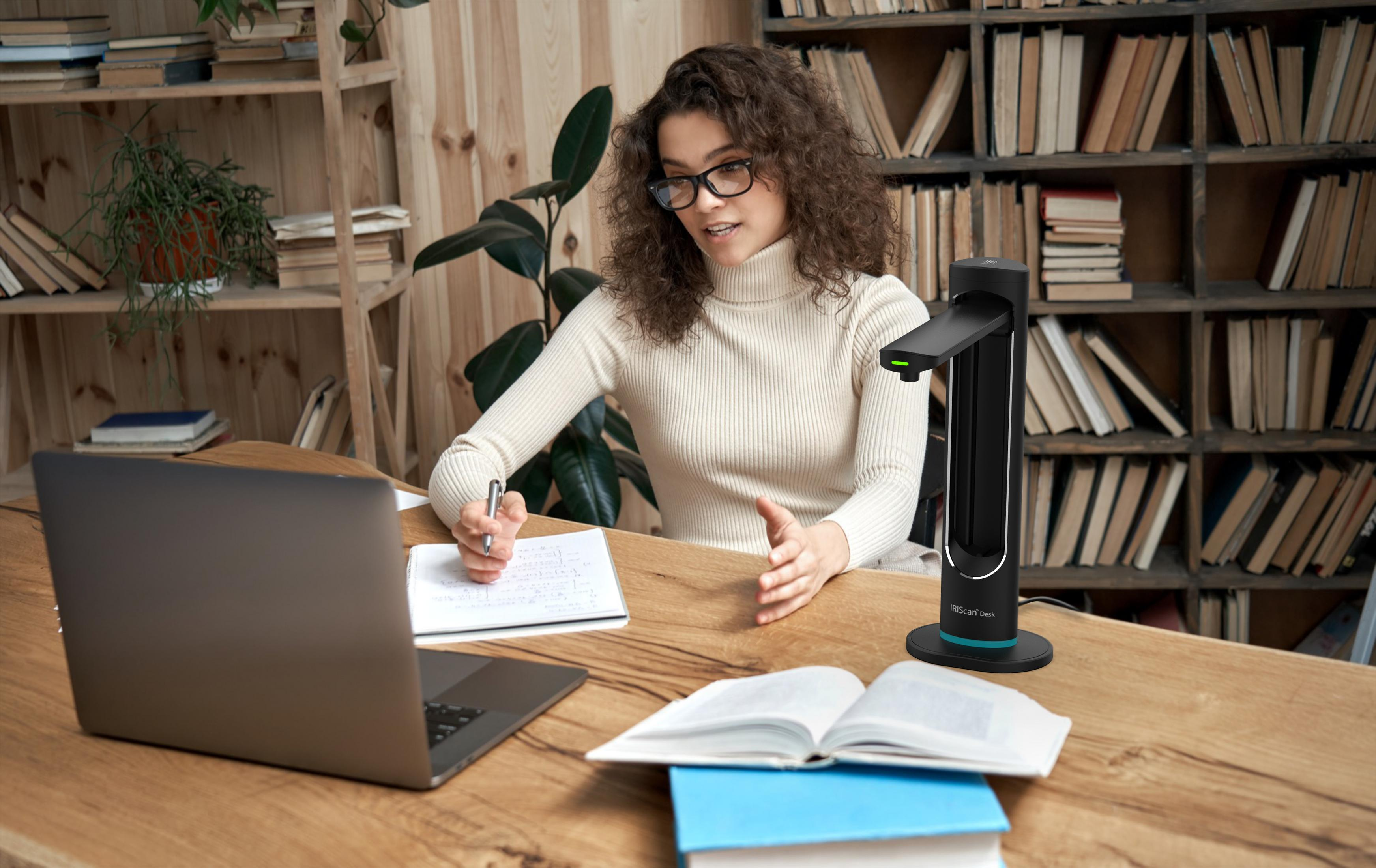 Mujer con gafas en videollamada, cuaderno, libros.