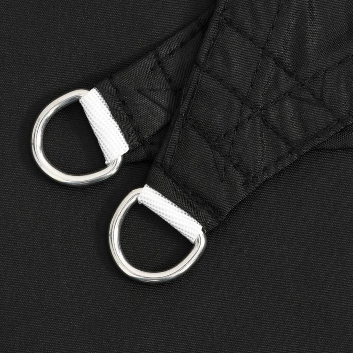 Nahaufnahme von zwei D-Ringen, die an schwarzem Stoff befestigt sind. Weißer Stoff sichert die Ringe.