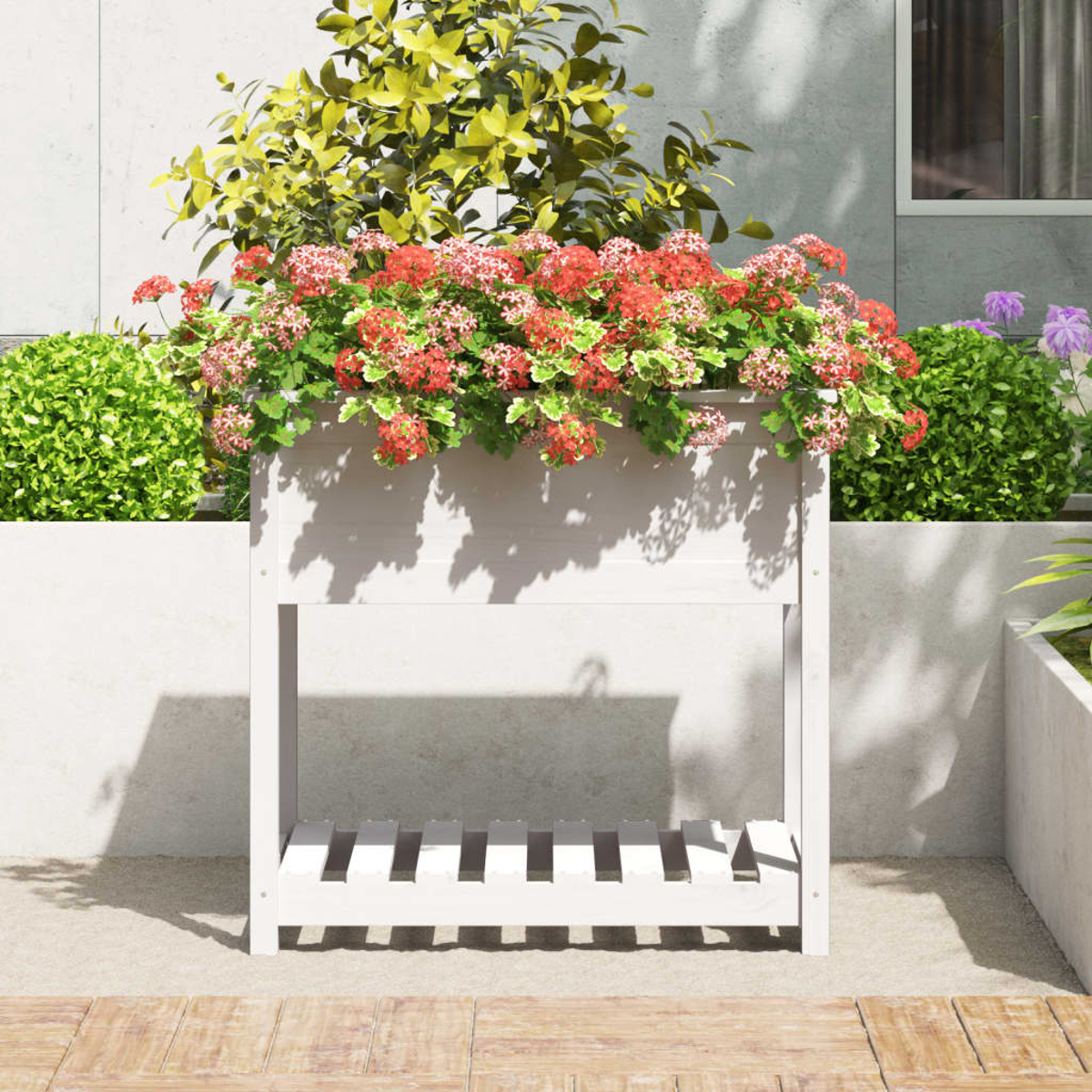 Weißer Holzpflanzer mit roten Blumen. Grüne Büsche im Hintergrund. Betonmauer sichtbar.