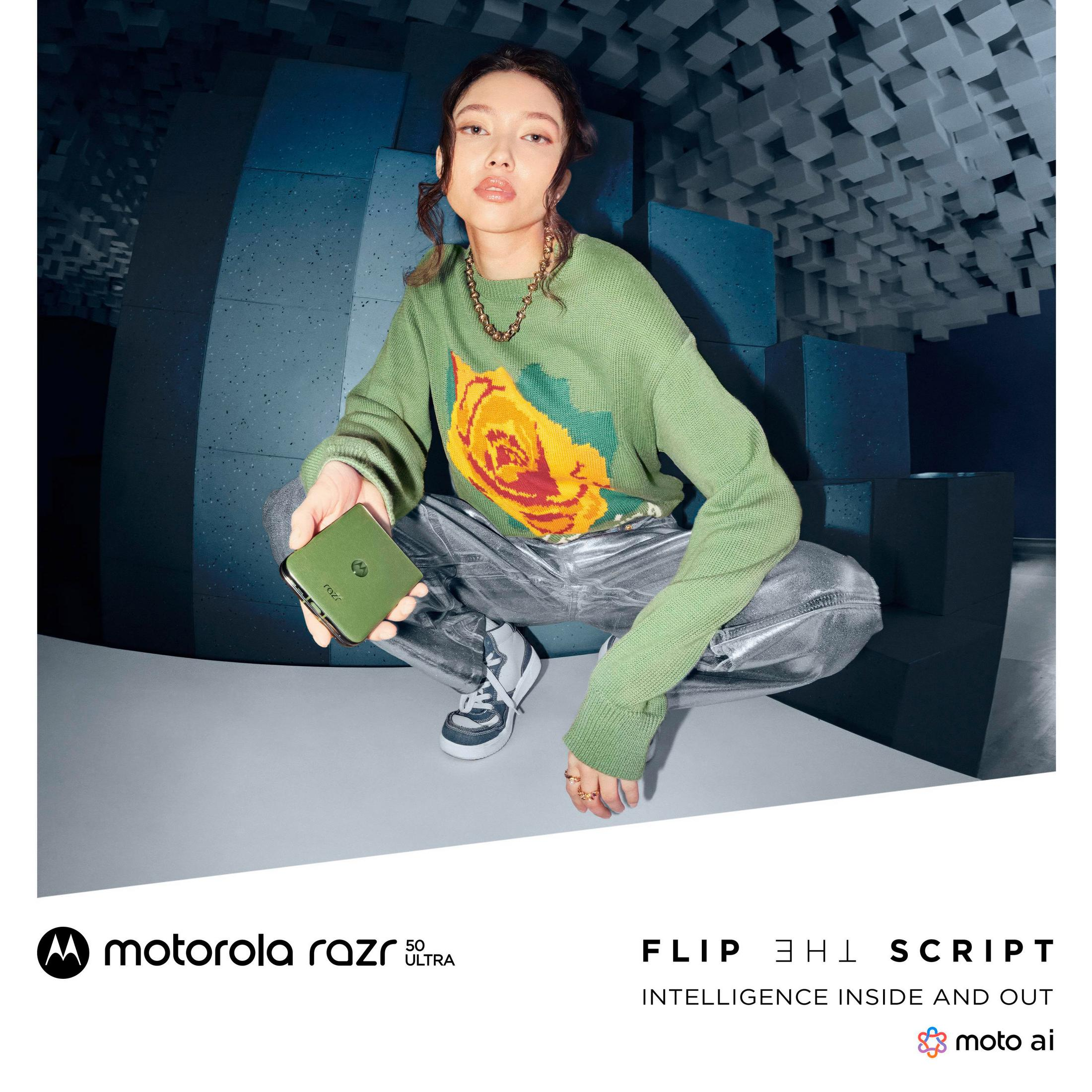 Kobieta w zielonym swetrze trzymająca zielony telefon. Tło to niebieska, teksturowana ściana.