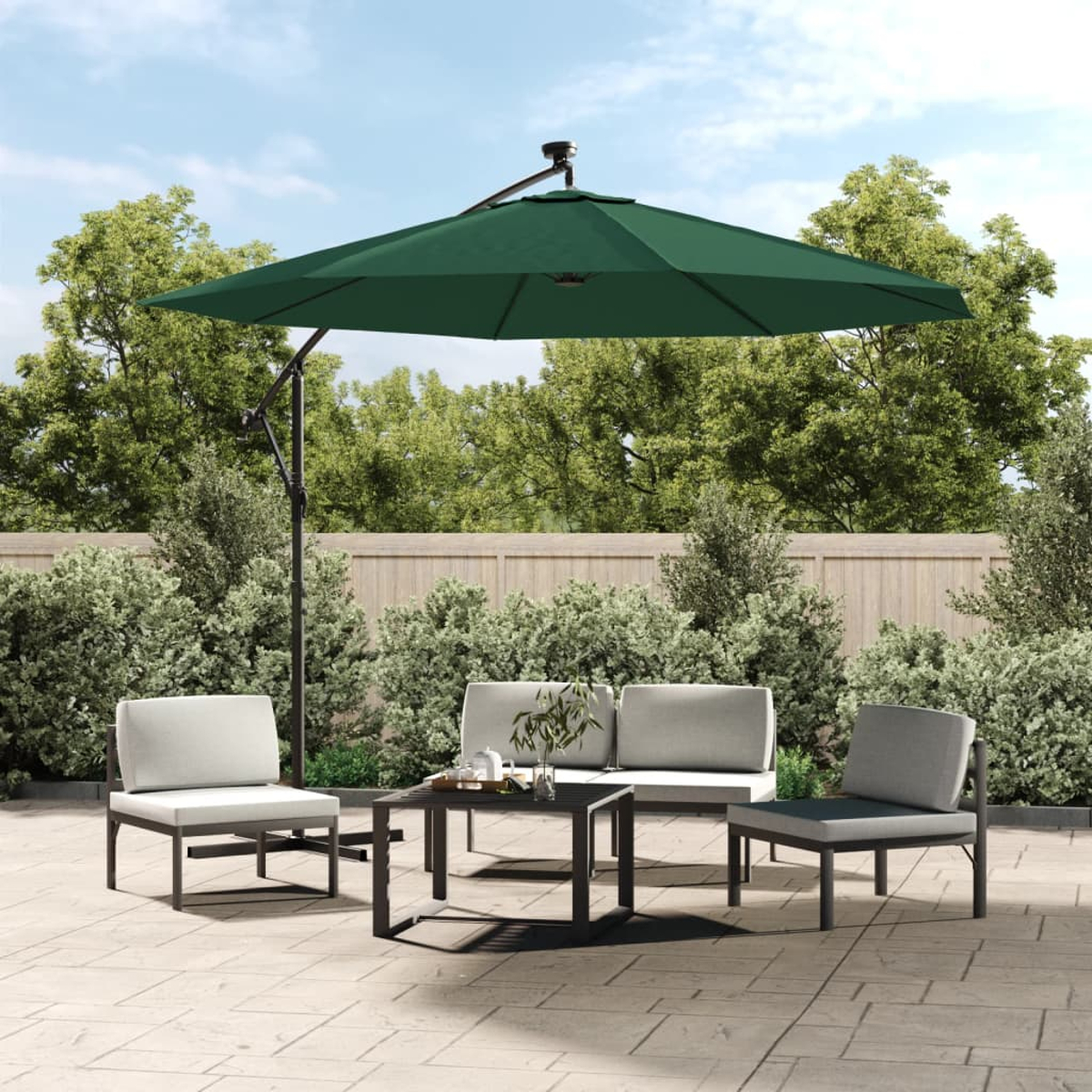 Terrassenszene mit einem grünen Sonnenschirm, Tisch, zwei Stühlen und einem Zweisitzer-Sofa. Bäume und Himmel im Hintergrund.