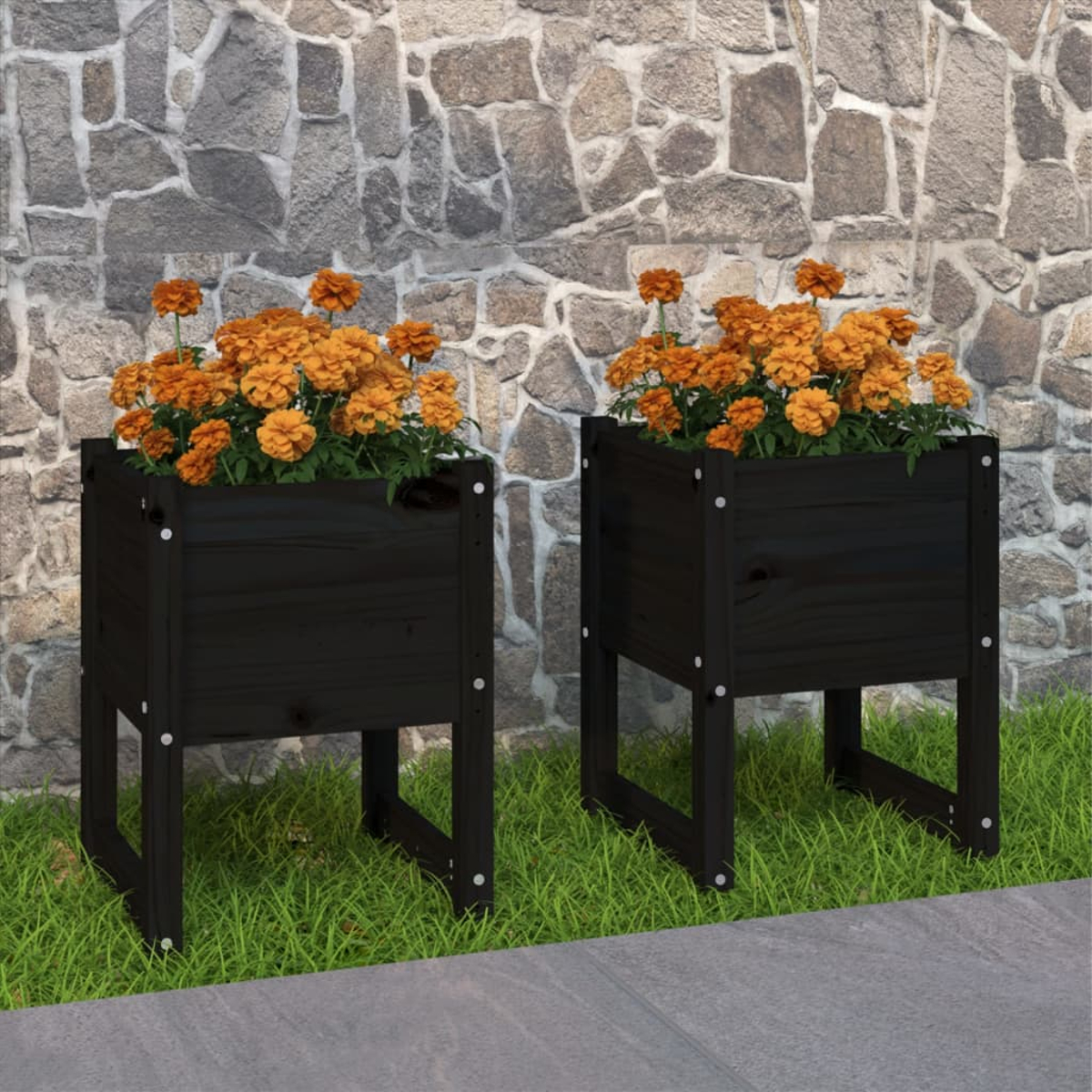 Zwei schwarze Pflanzgefäße aus Holz mit orangefarbenen Blumen vor einer Steinmauer. Die Pflanzgefäße stehen auf Gras.