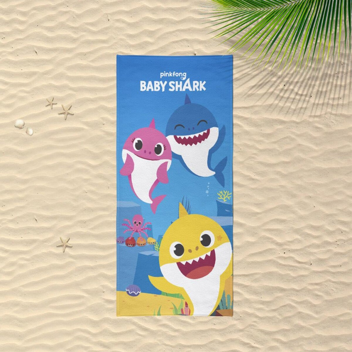 Toalla de playa Baby Shark. Tres Baby Sharks con fondo azul, sobre arena.
