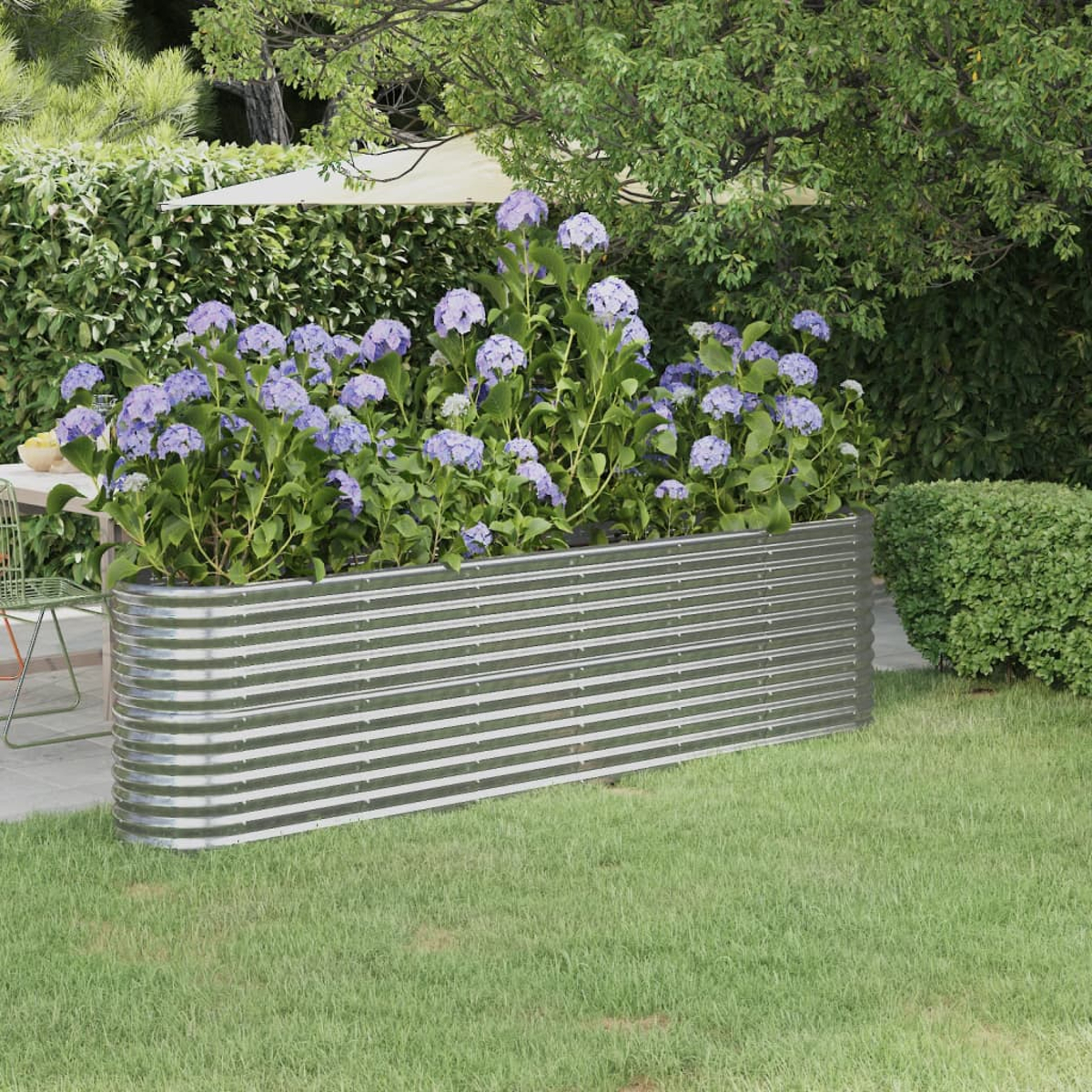 Ein Gartenbeet im Freien mit leuchtend blauen Hortensien und einem metallischen, gewellten Beet.