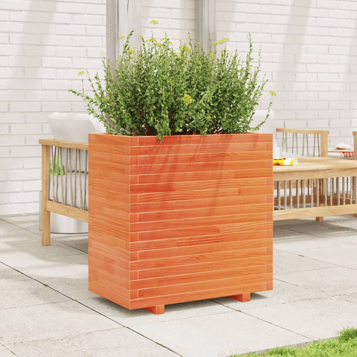 Quadratischer Holzpflanzer gefüllt mit Pflanzen auf einer Terrasse mit Steinfliesen.